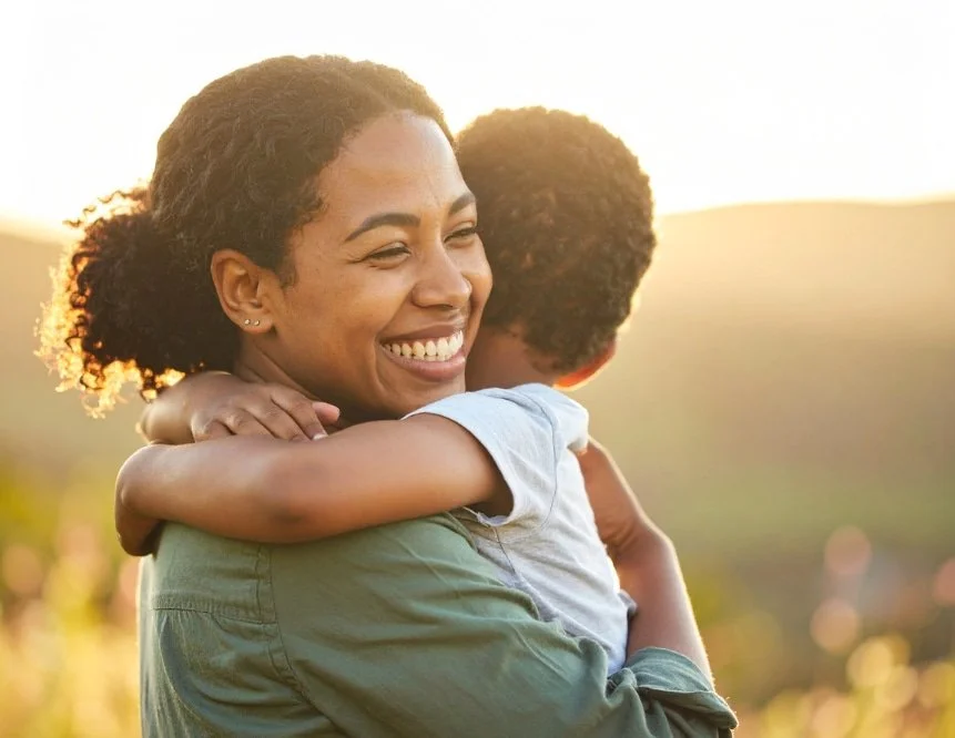 Parent and child embracing outdoors, representing healing, connection, and generational change.