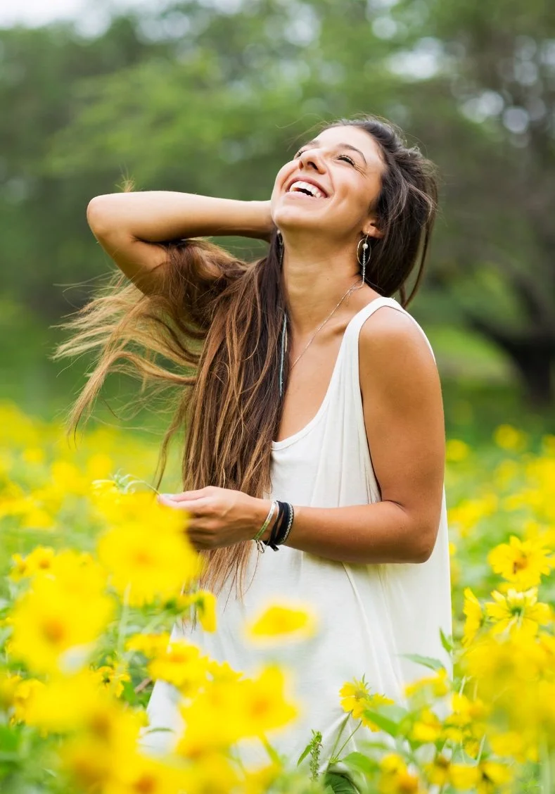 Young woman laughing in a field of yellow flowers—brighter days after acute trauma care in Bryn Mawr & Newark, DE.