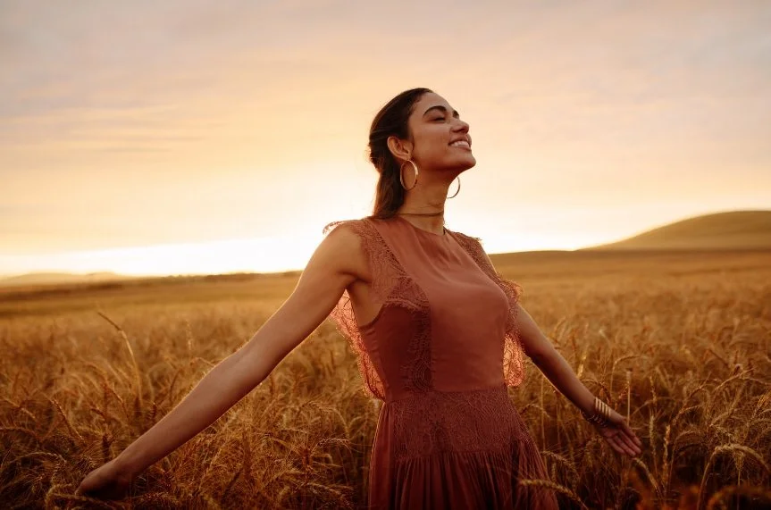 Woman standing in a field feeling calm and grounded, representing healing from trauma through EMDR therapy
