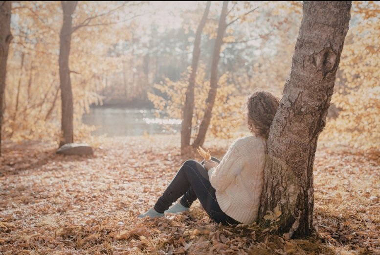 Woman sitting alone outdoors reflecting on the lasting effects of PTSD from childhood and trauma healing through EMDR therapy