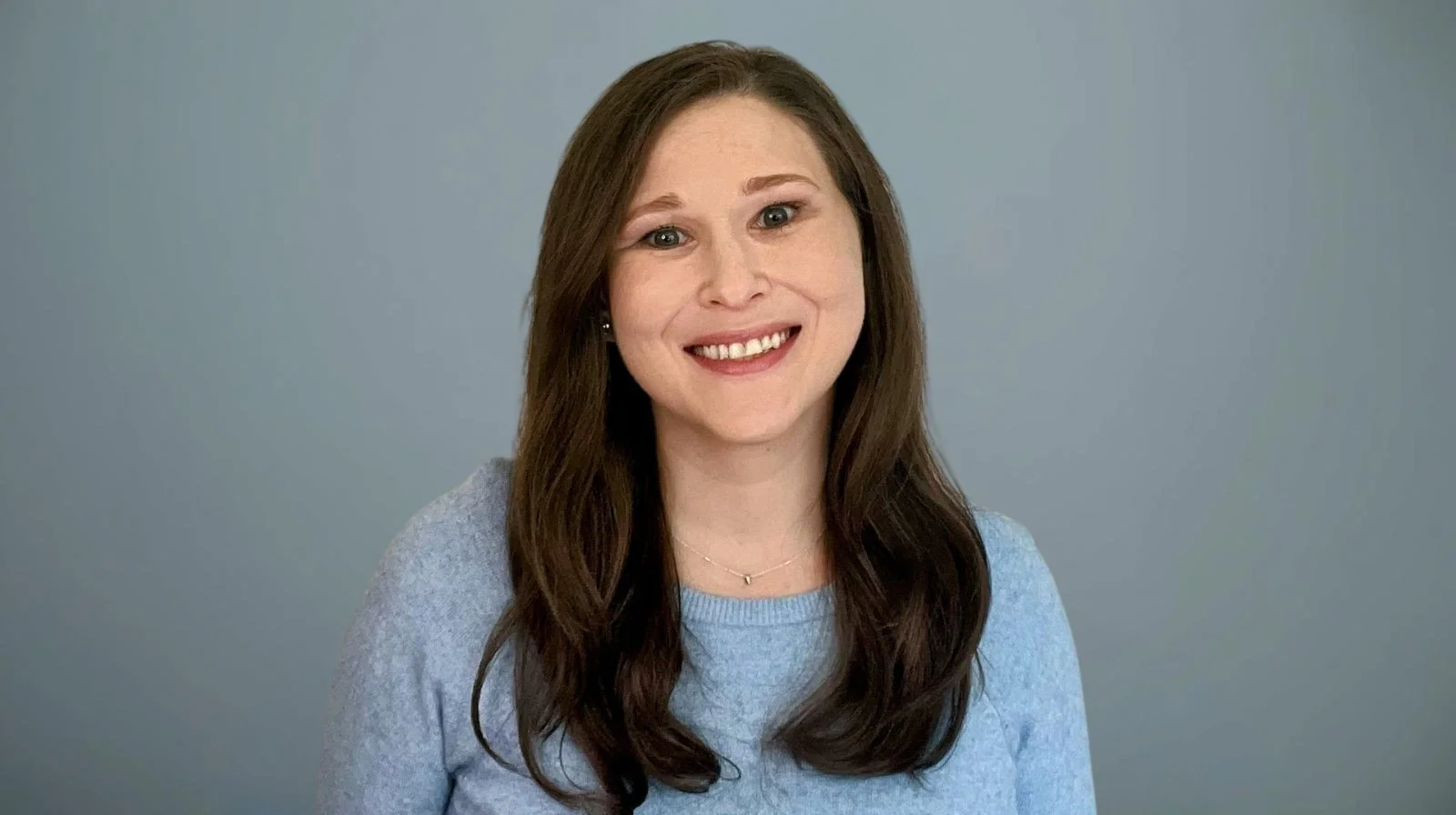 Professional headshot of Sarah Sternlieb, MS, LPC, smiling against a gray background — licensed therapist specializing in EMDR and online trauma therapy in Pennsylvania and Delaware.