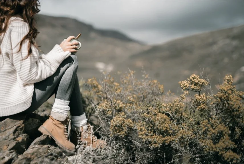Woman sitting alone outdoors reflecting on the effects of complex trauma, CPTSD, and childhood trauma