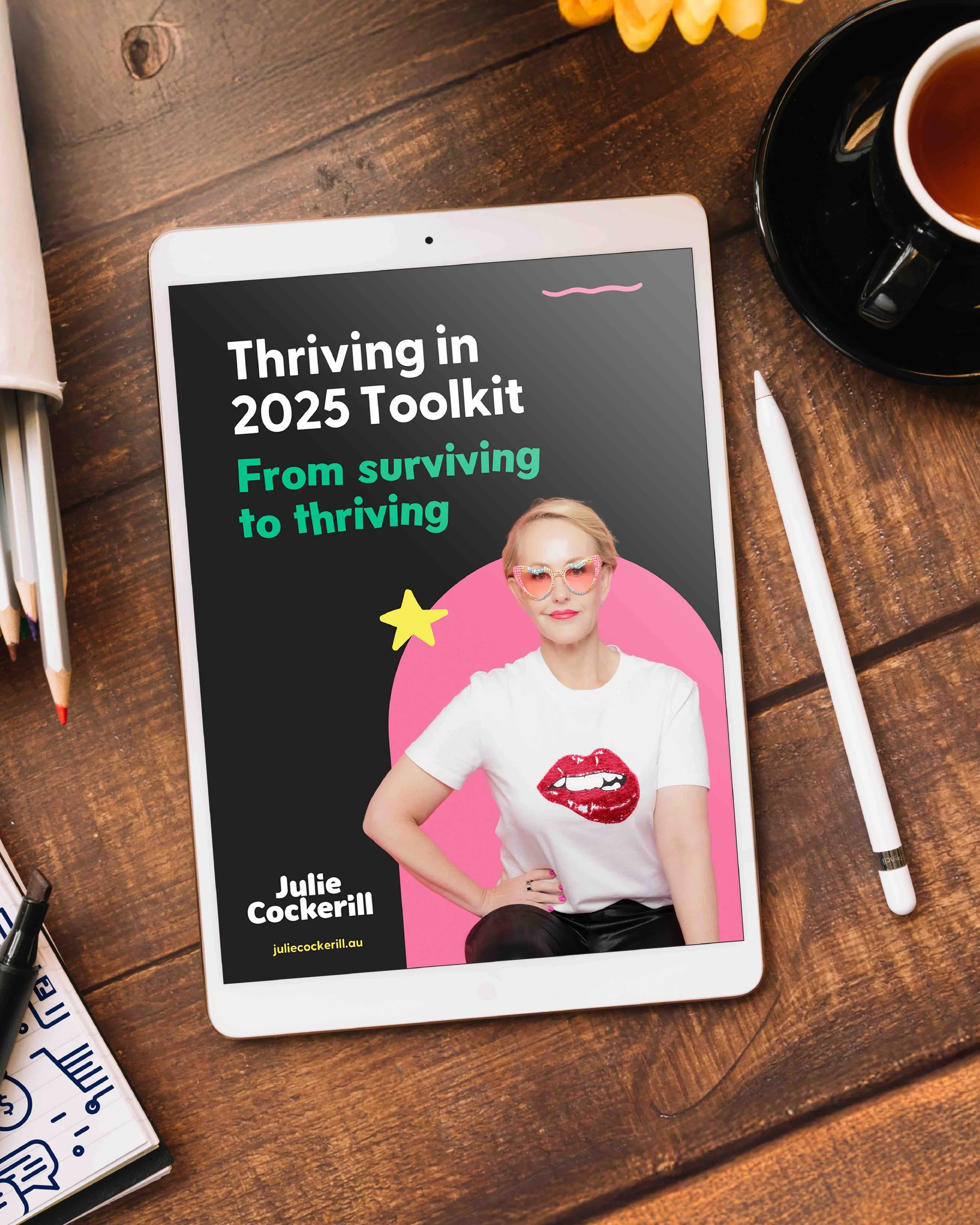 Freelance Graphic Designer Melbourne. A white tablet displaying a book cover titled "Thriving in 2025 Toolkit: From surviving to thriving" by Julie Cockerill,
