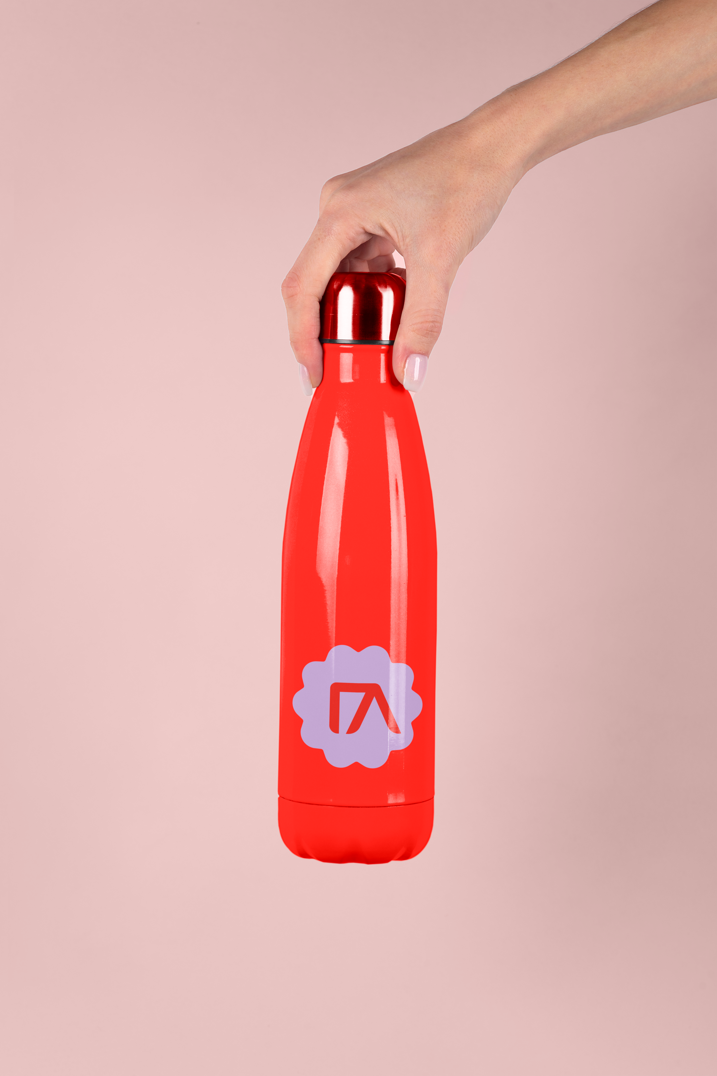 Freelance Graphic Designer Melbourne. A hand holding a red reusable water bottle with a Pilates logo on it, against a pink background.