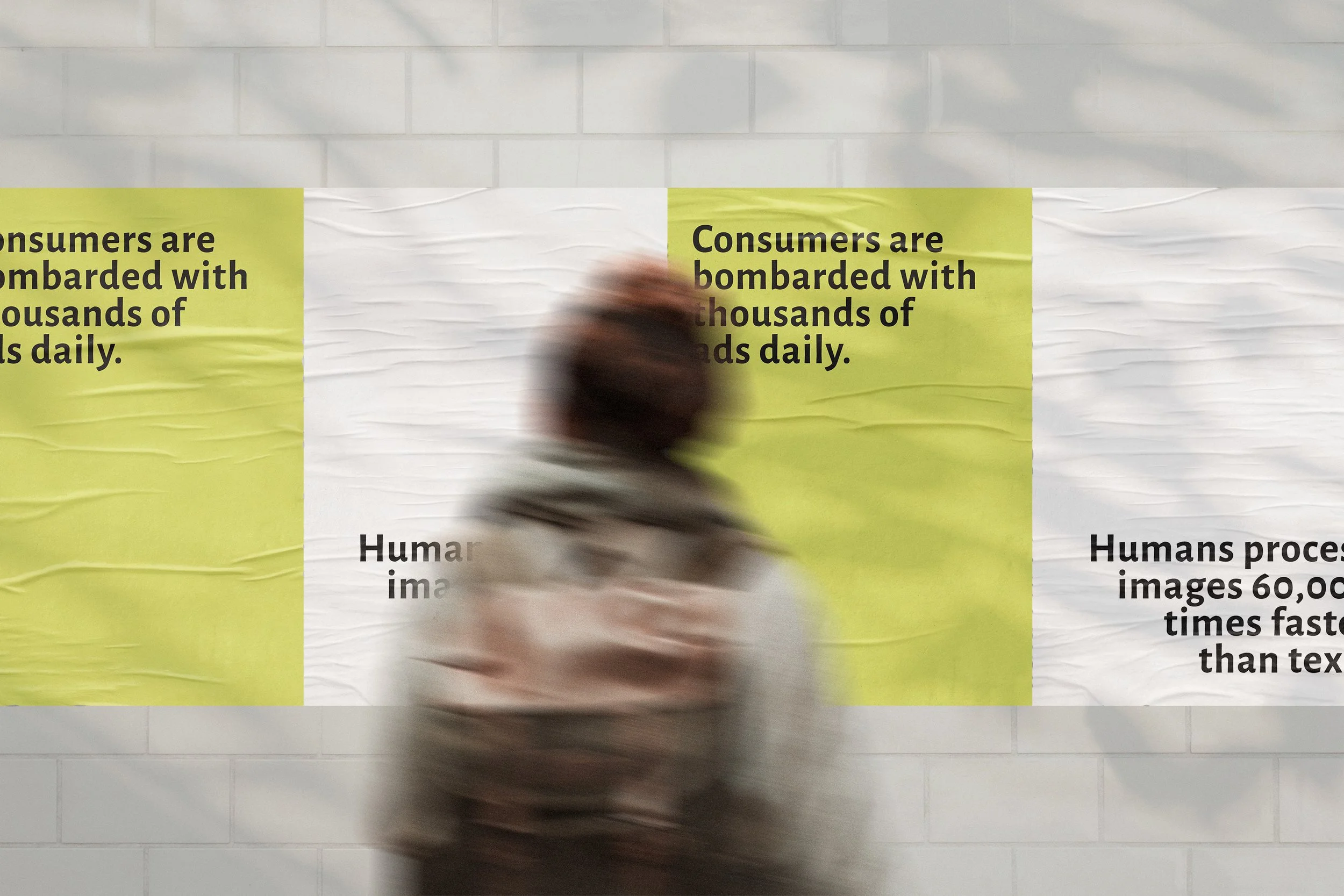 Freelance Graphic Designer Melbourne. A blurred person walking past a large poster with text on a light-colored brick wall.