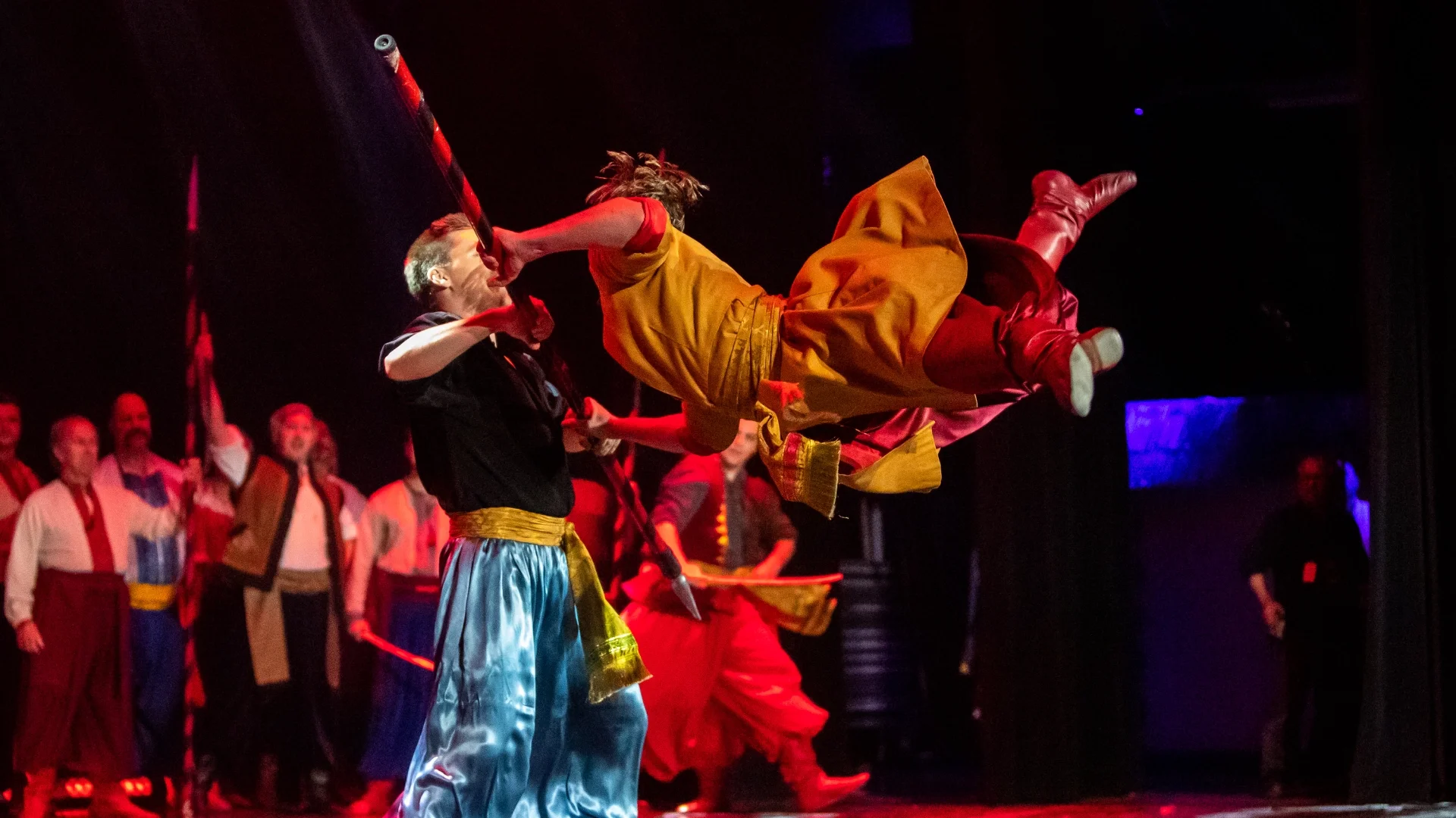 Rusalka Ukrainian Dance Ensemble performing an acrobatic Cossack-style fight scene on stage, showcasing traditional Ukrainian martial dance choreography in Winnipeg