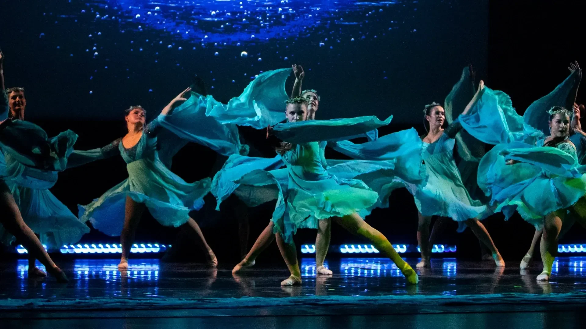 Rusalka Ukrainian Dance Ensemble women performing a modern theatrical dance in flowing turquoise dresses, evoking underwater motion and artistry during a contemporary segment in Winnipeg.