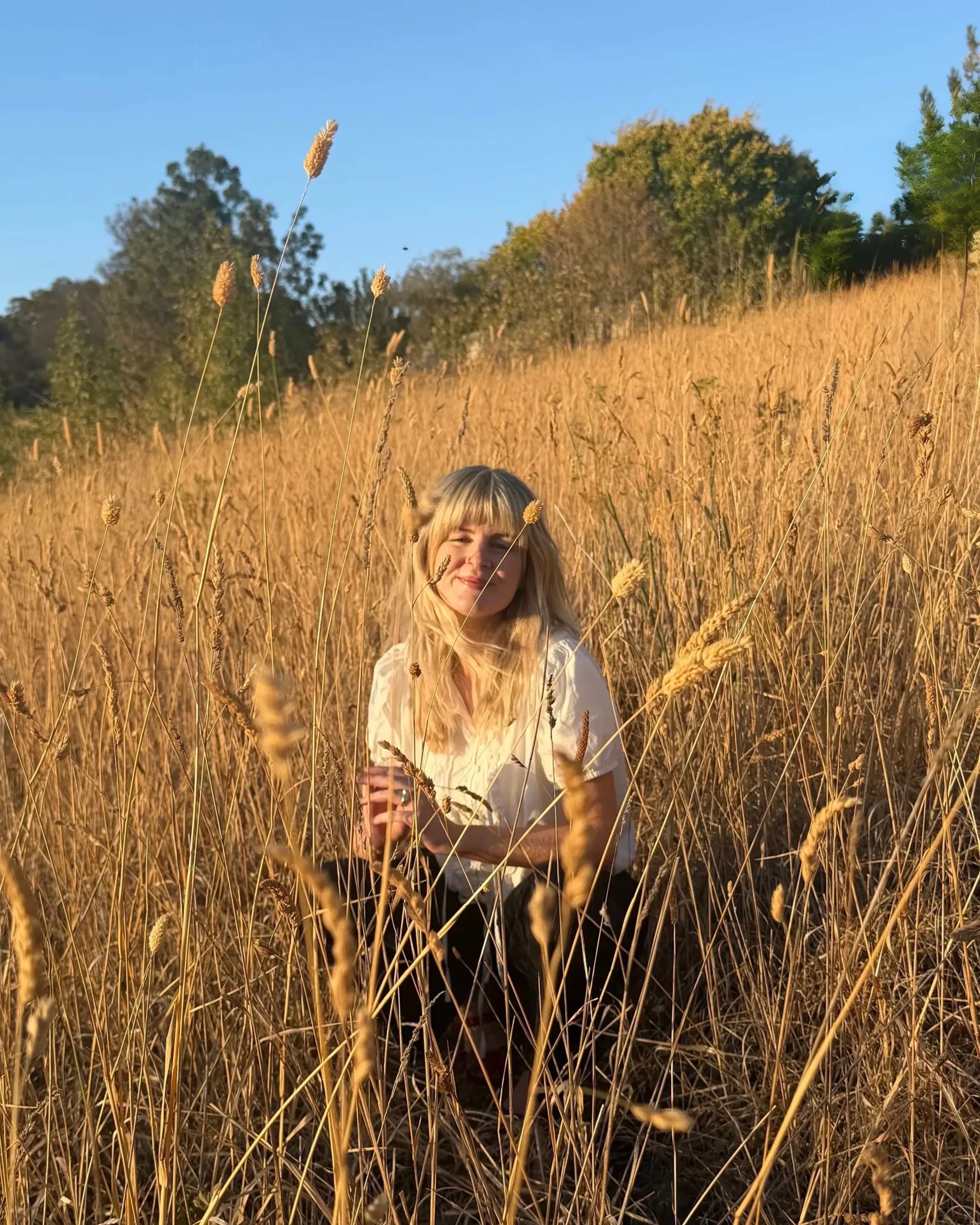 allie sitting in a field of grass smiling
