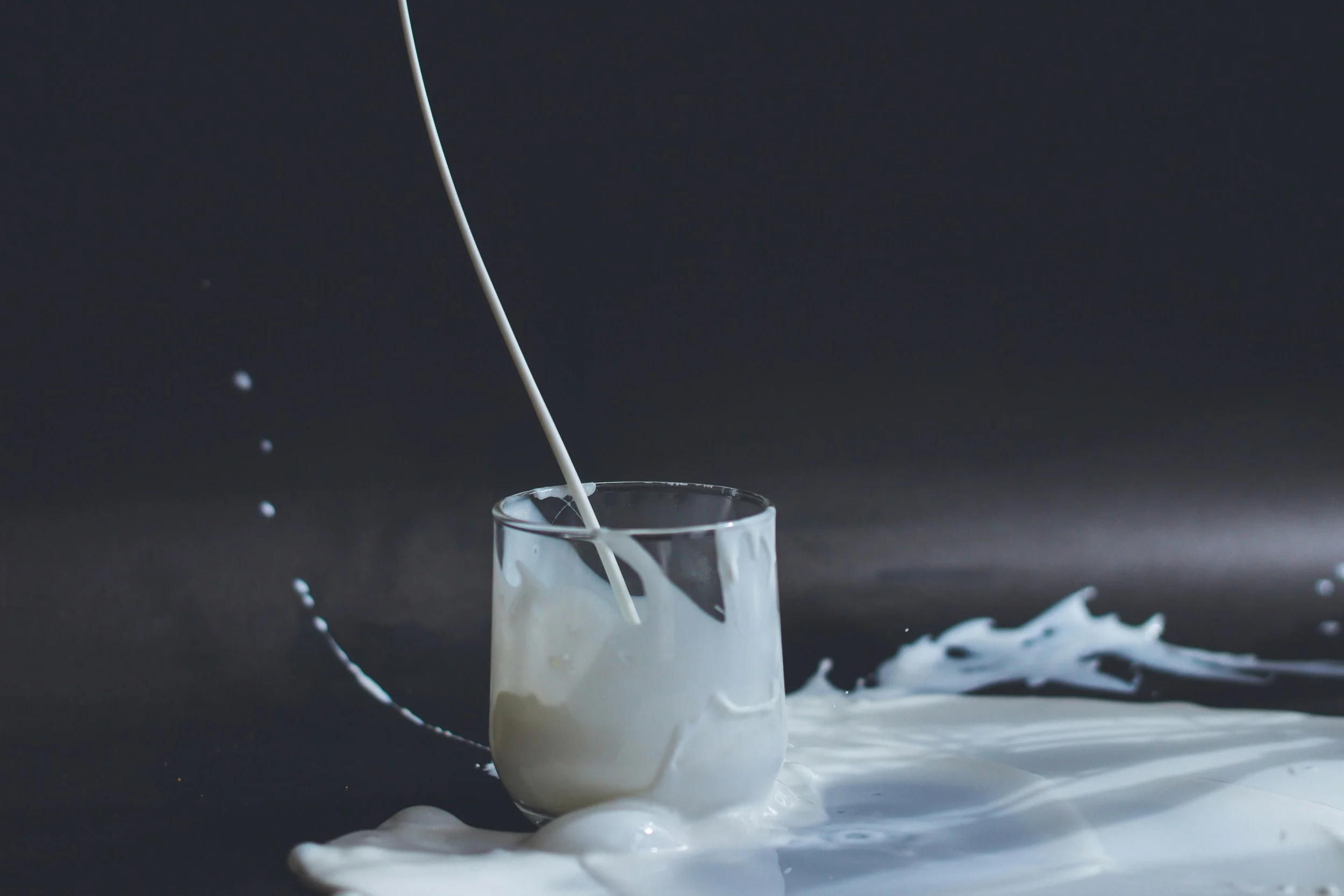 milk being poured into a glass, and spilled