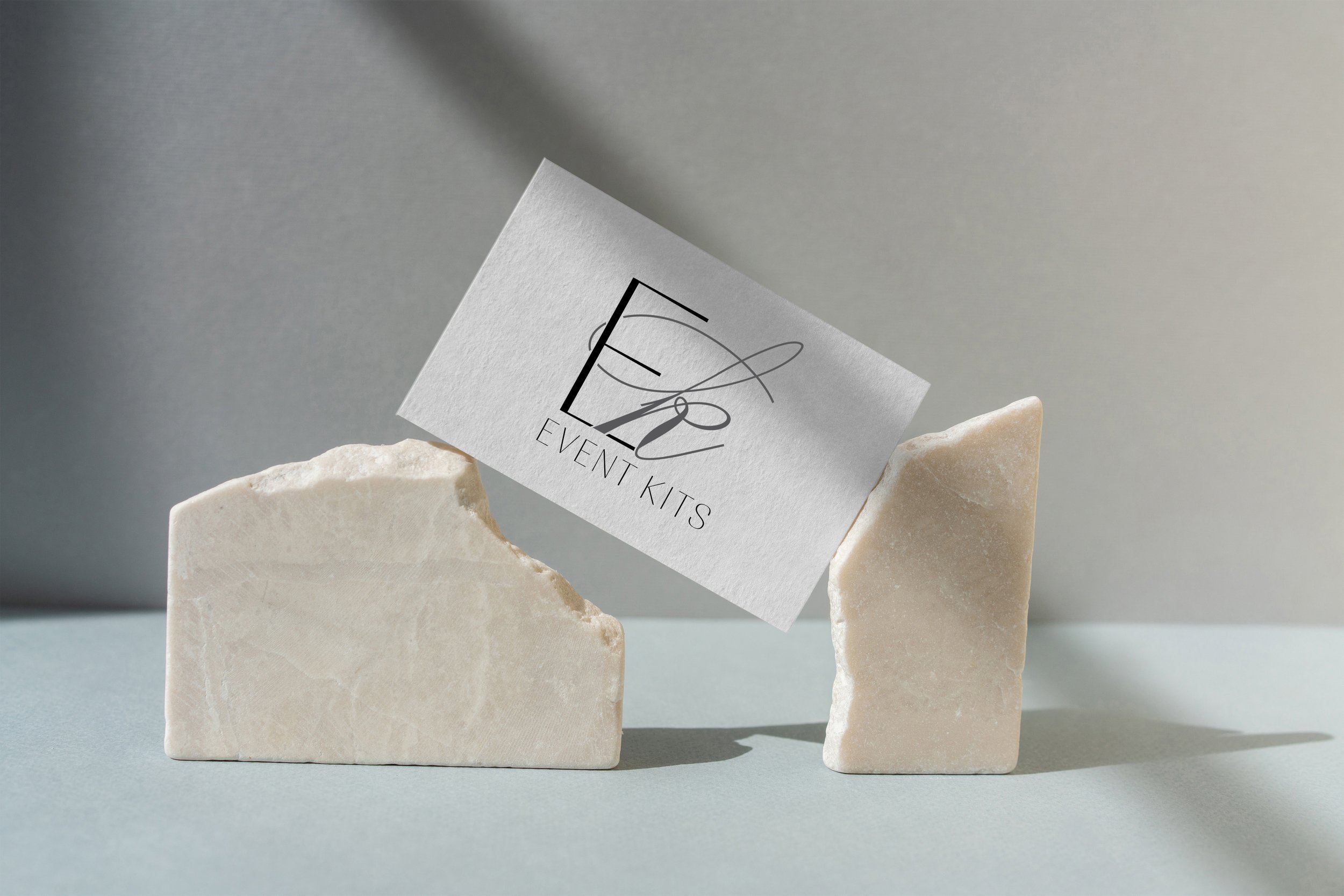 A business card for Event Kits resting on two beige stone blocks.