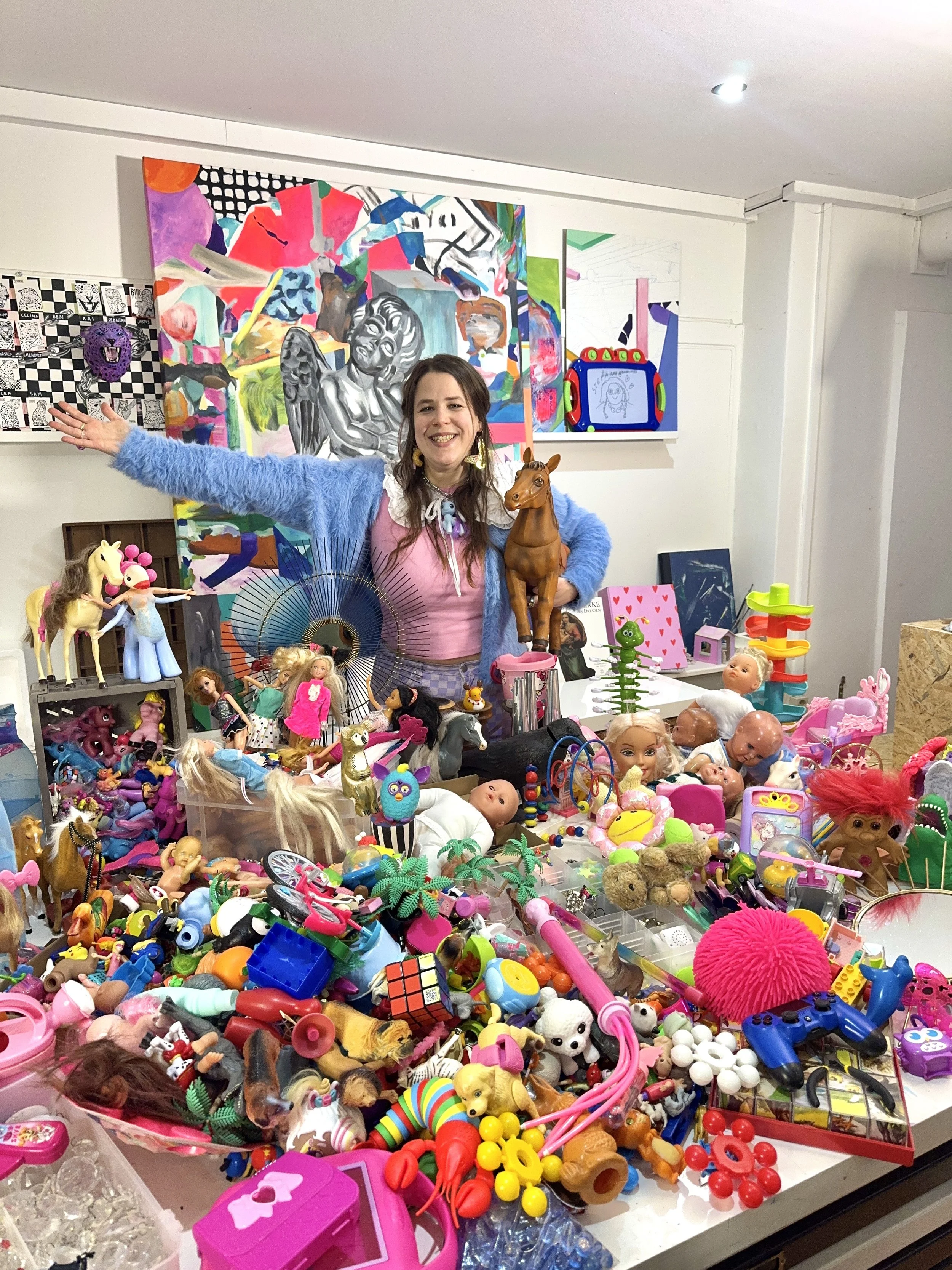 Artist standing behind a large table covered with colorful plastic toys
