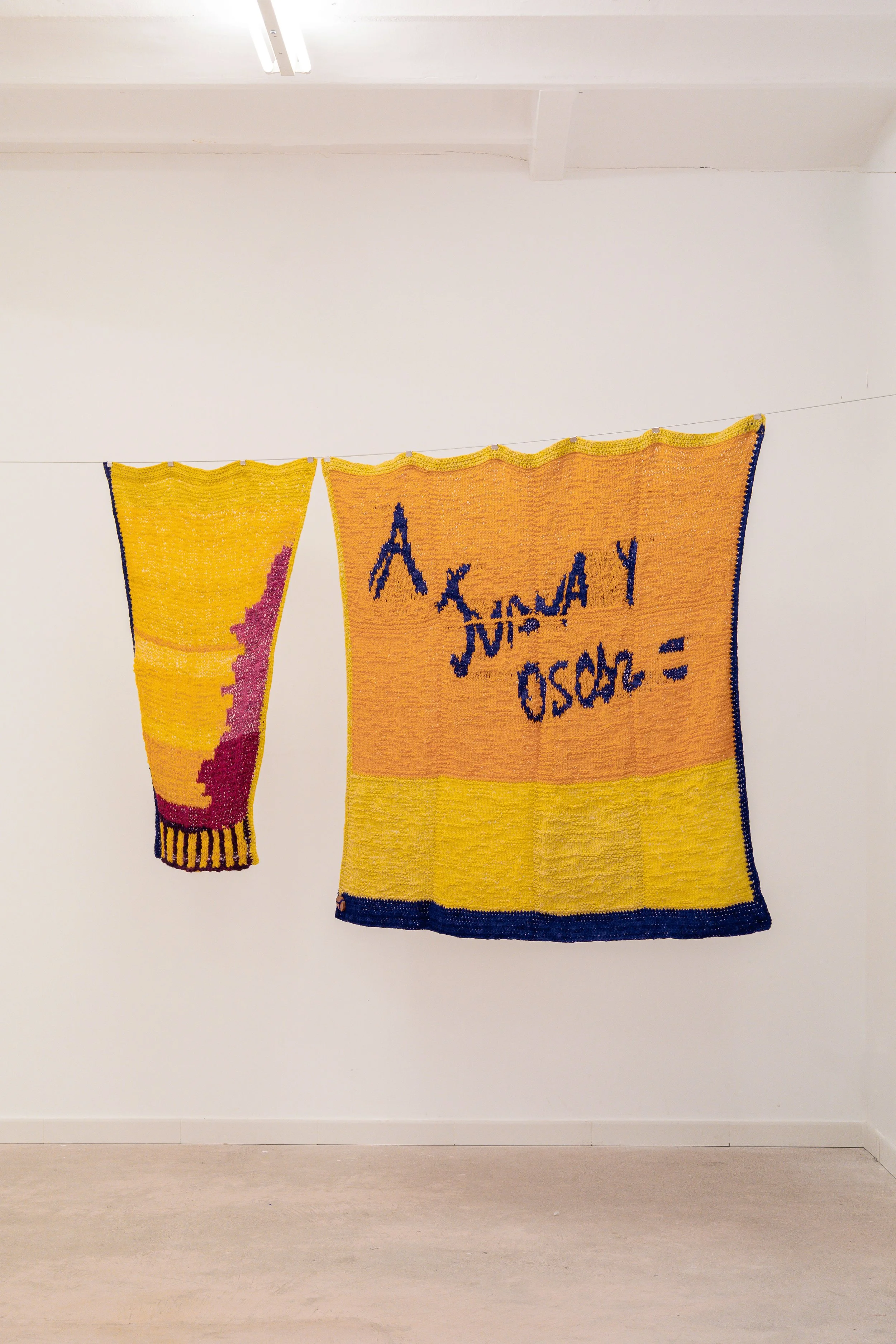 A Juana y Oscar, 2026 // Sheep's wool (Hand-knitted with two needles and crochet) // Total dimensions: 134 x 215 x 3 cm Dimensions of the left piece: 120 x 77 x 3 cm Dimensions of the right piece: 134 x 138 x 3 cm