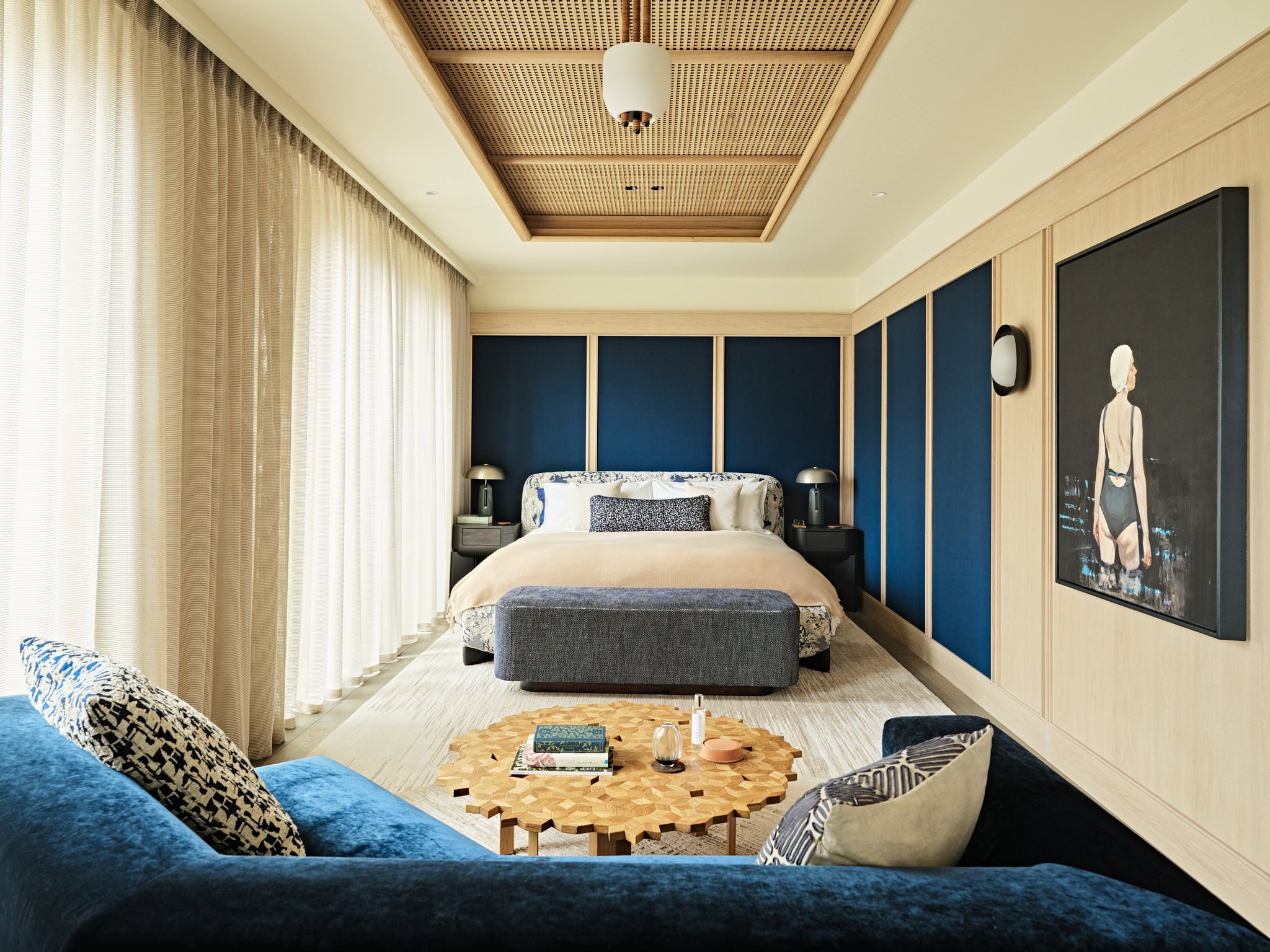 Spacious modern bedroom with blue panels and blue sofa, interior design by Carden Cunietti