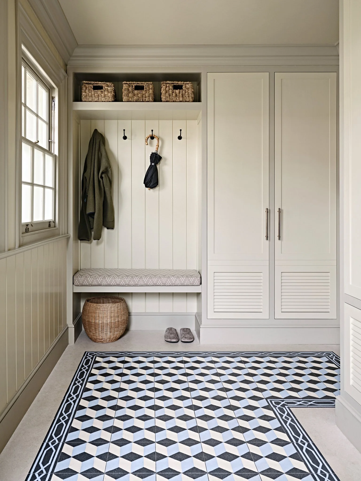 Reception boot room with cream panelling in modern home with graphic blue floor tiles, designed by Bryan O'Sullivan Studio