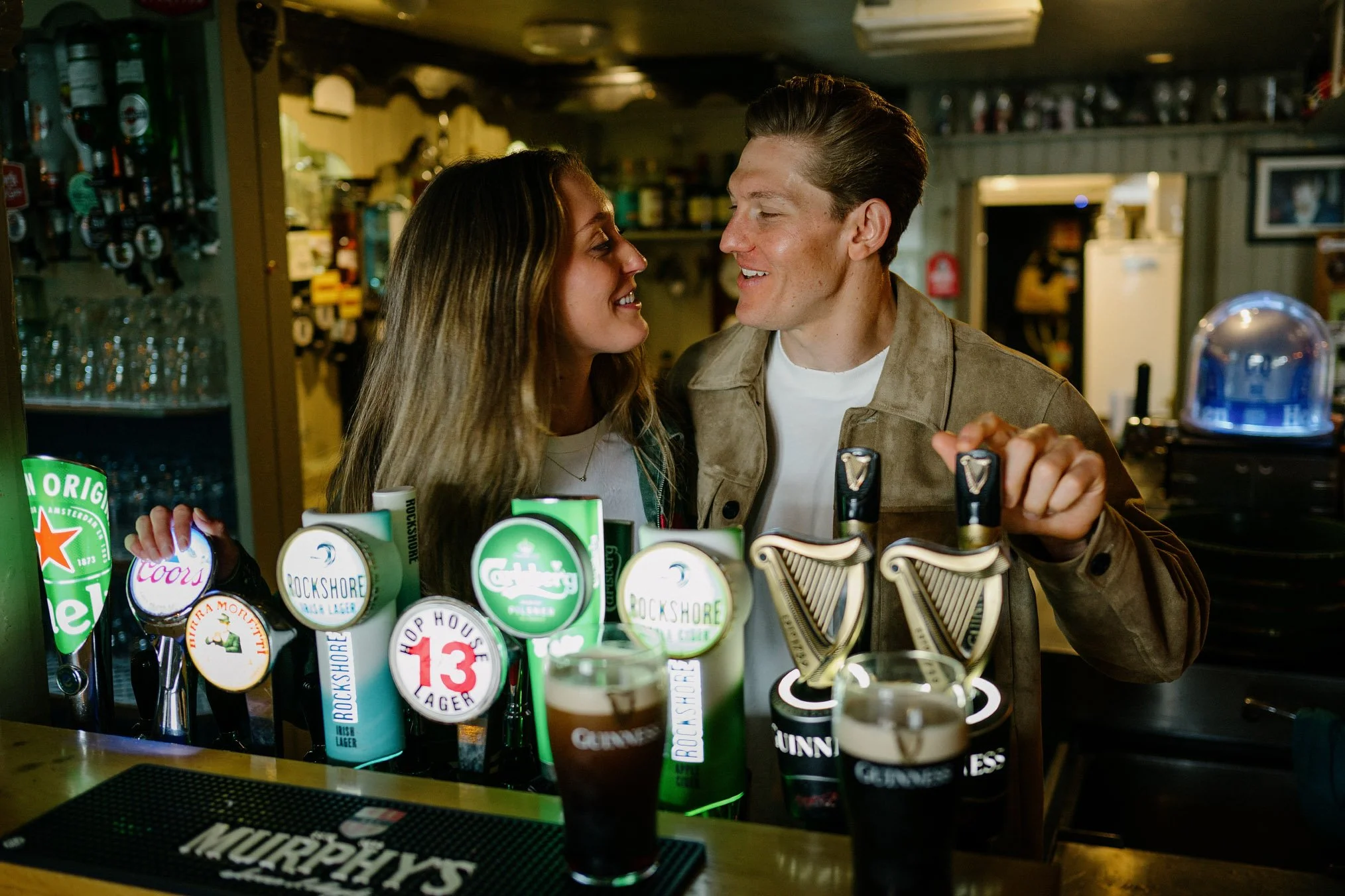 Newly engaged couple laughing together behind the bar at McDermott's pub in Doolin, County Clare