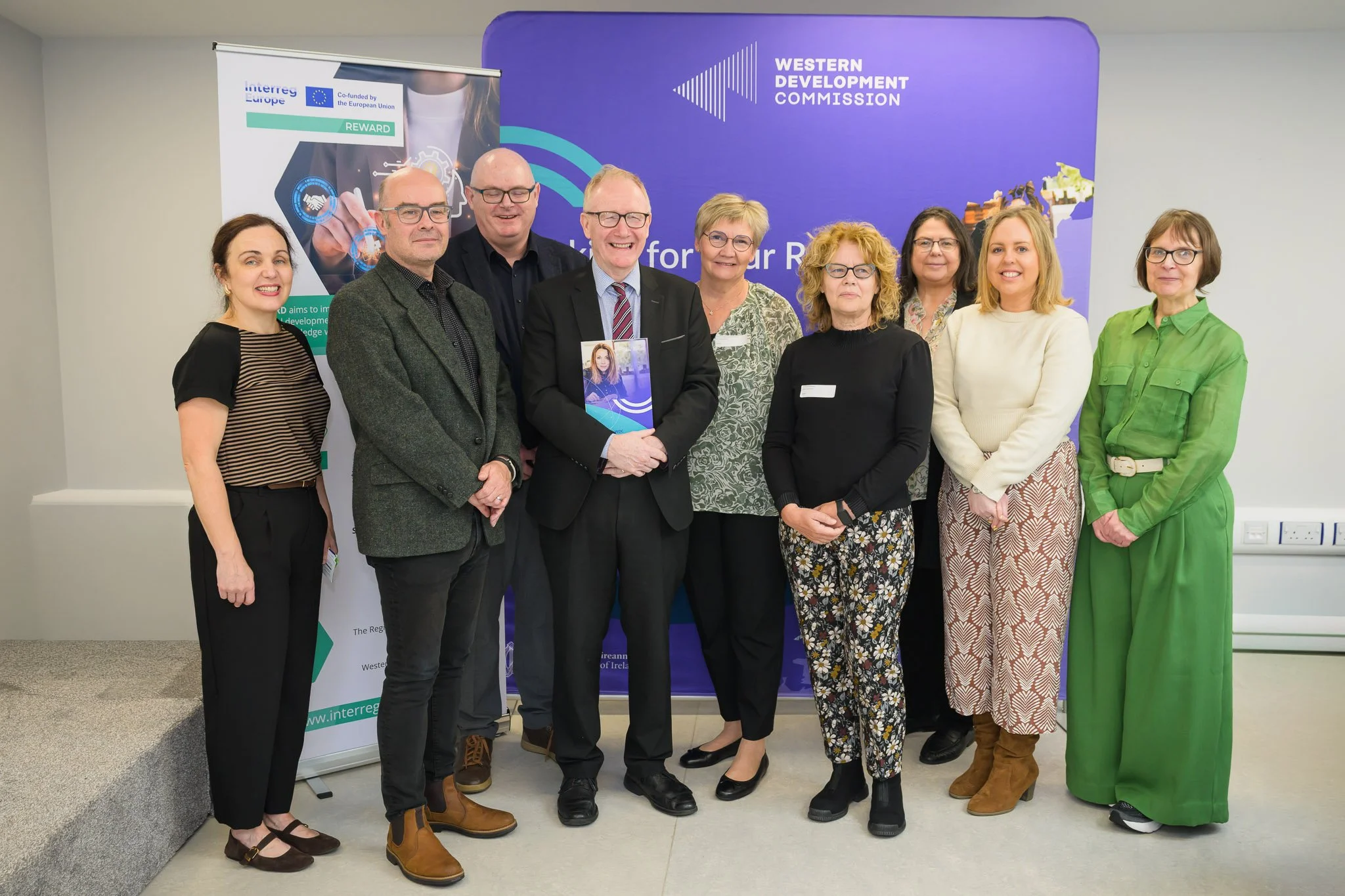 Western Development Commission team and partners with the REWARD report in front of the WDC and Interreg Europe REWARD banners