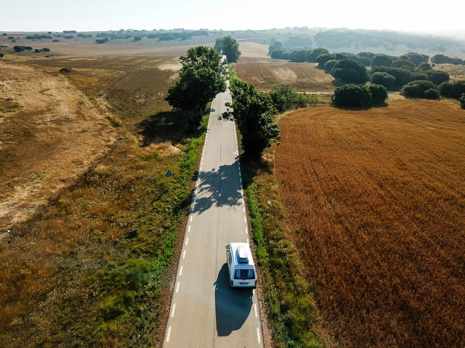 Aerial view of a service van on a rural road through farmland