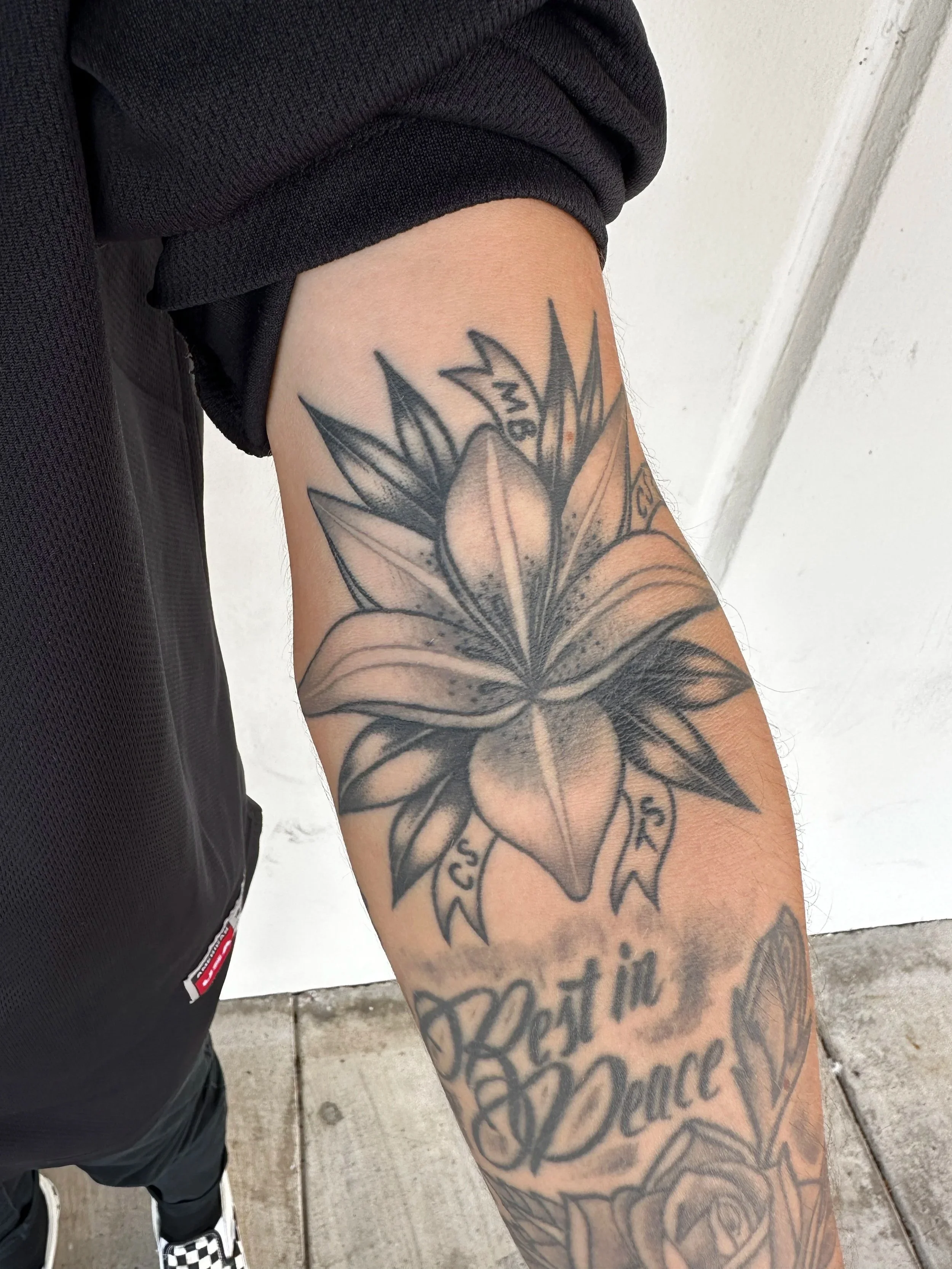 This black and grey lily tattoo was for my client who wanted to make sure he included his family in many of his tattoos. The ribbons are the initials for some of his family members. 