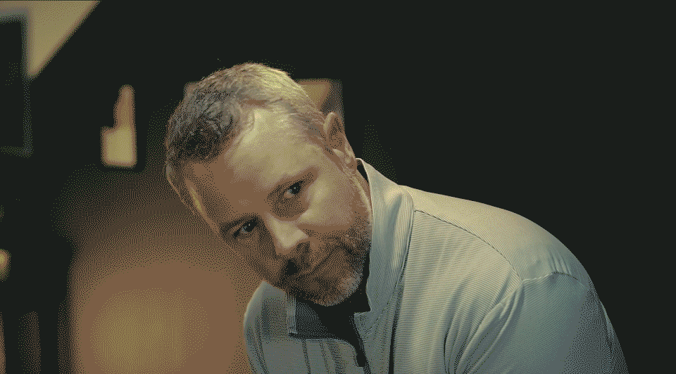 Golfer finishing swing inside Optimum Golf indoor simulator with mountain course backdrop, demonstrating realistic virtual practice environment.