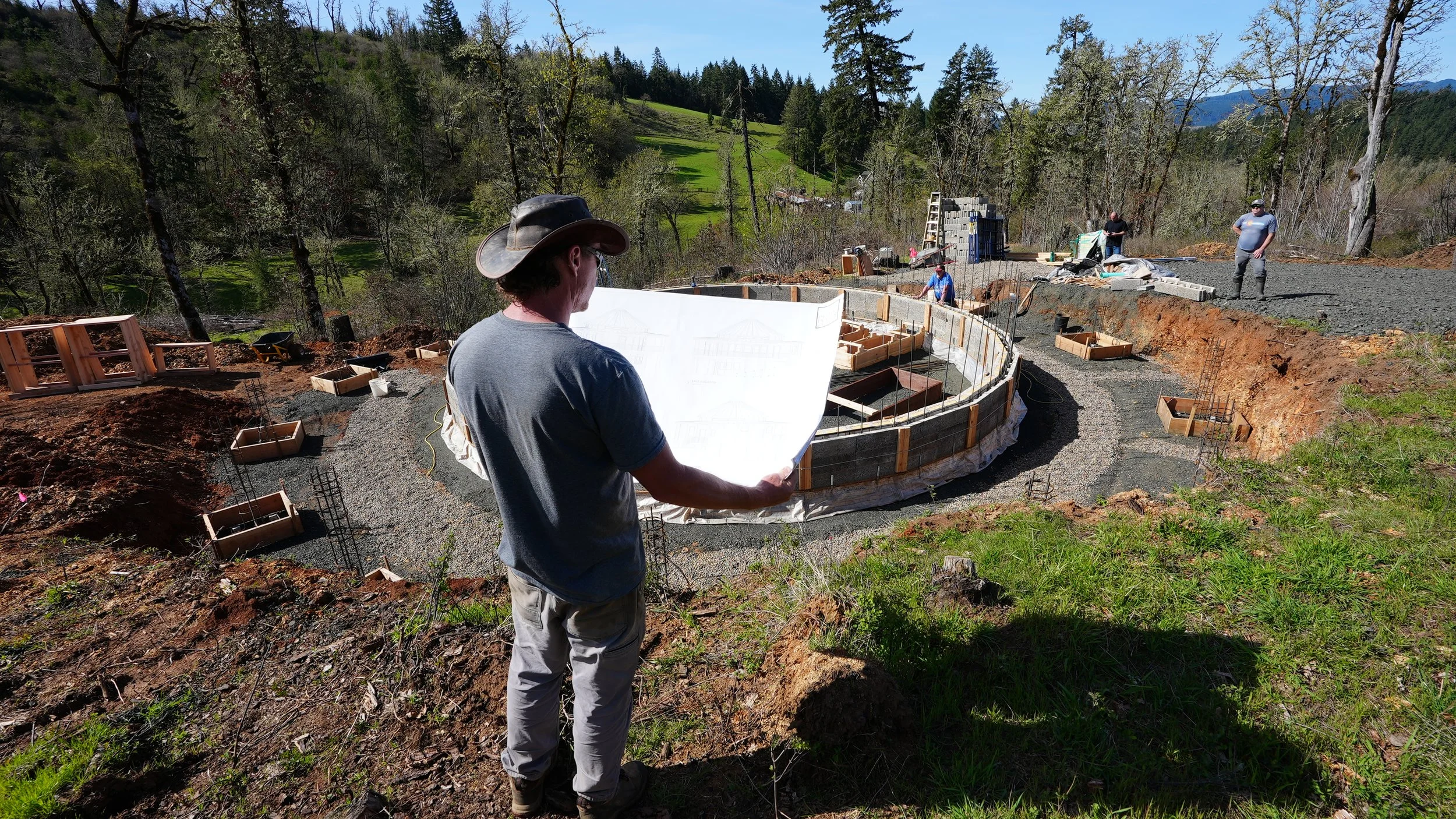 Man looking at blueprints in front of circular home structure. 