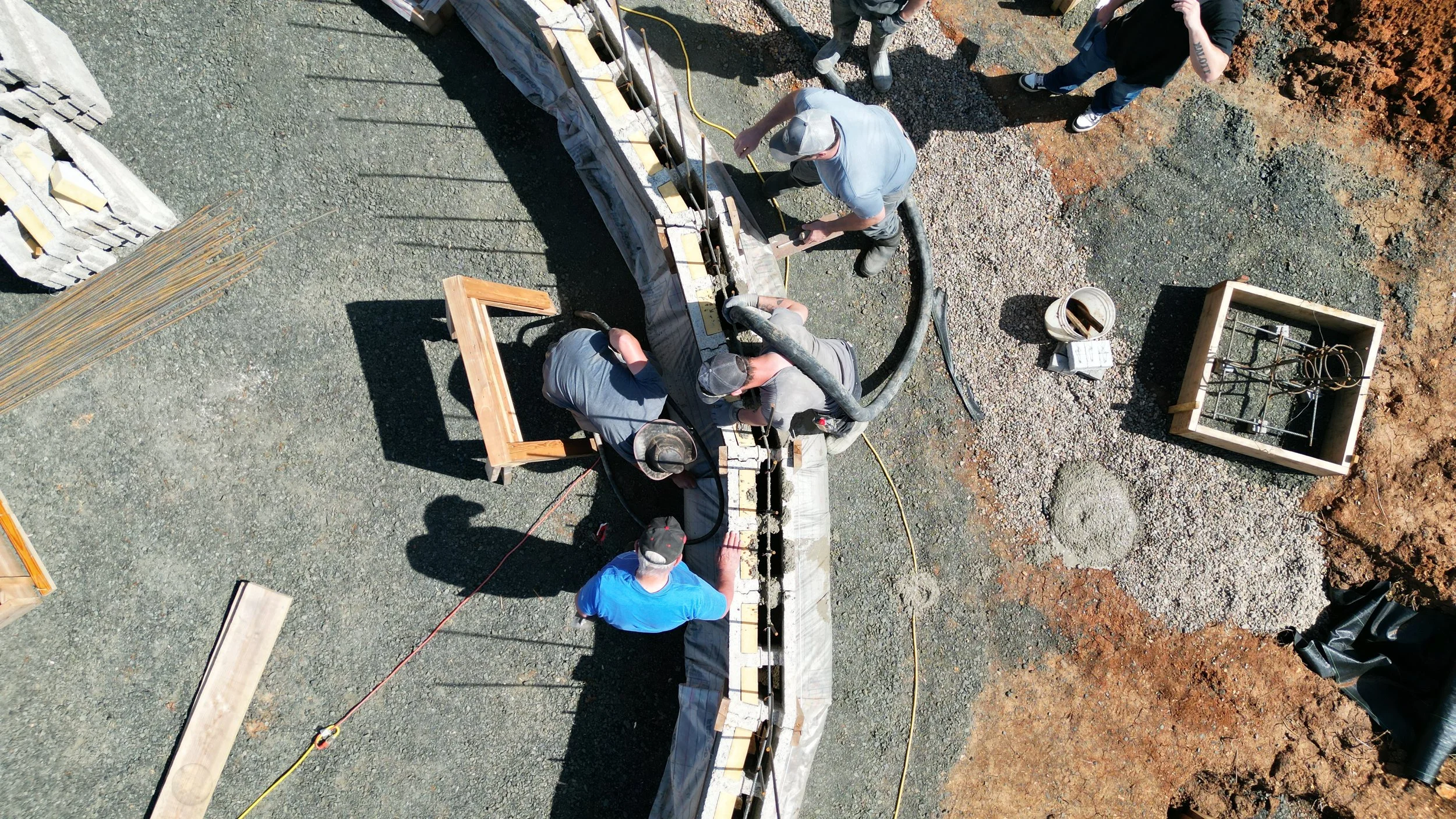 Workers pumping concrete into circular home structure.