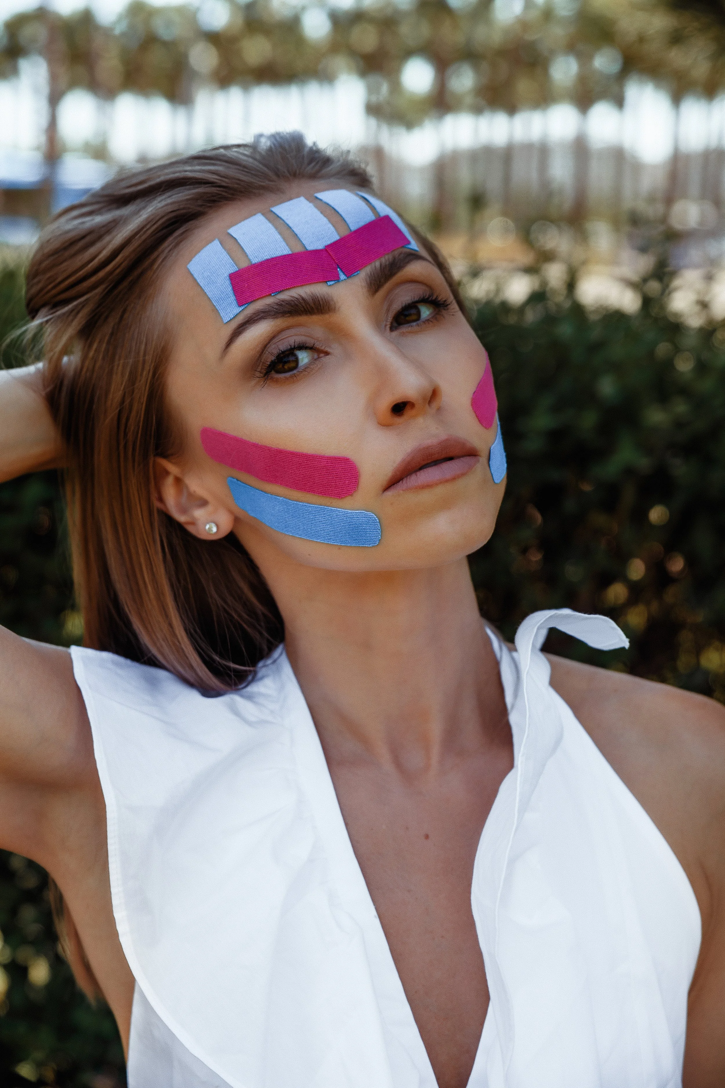 Face taping technique using colorful tape for lifting skin, smoothing wrinkles, and sculpting facial contours naturally.