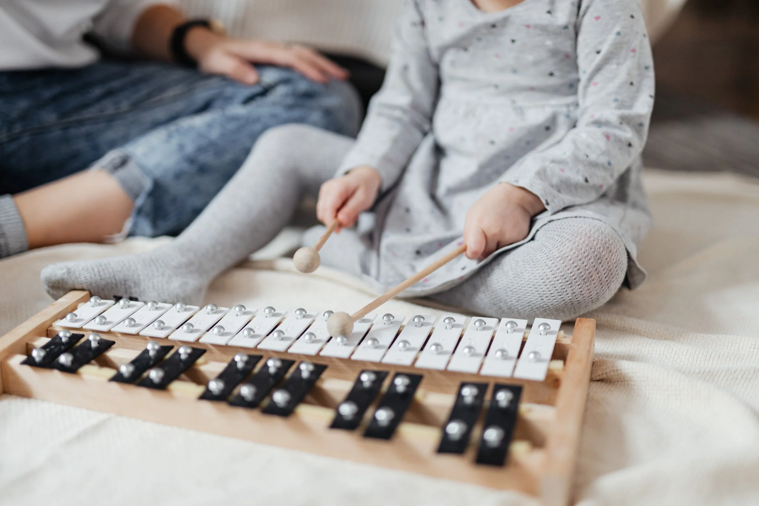young child and parent playing a xylophone together