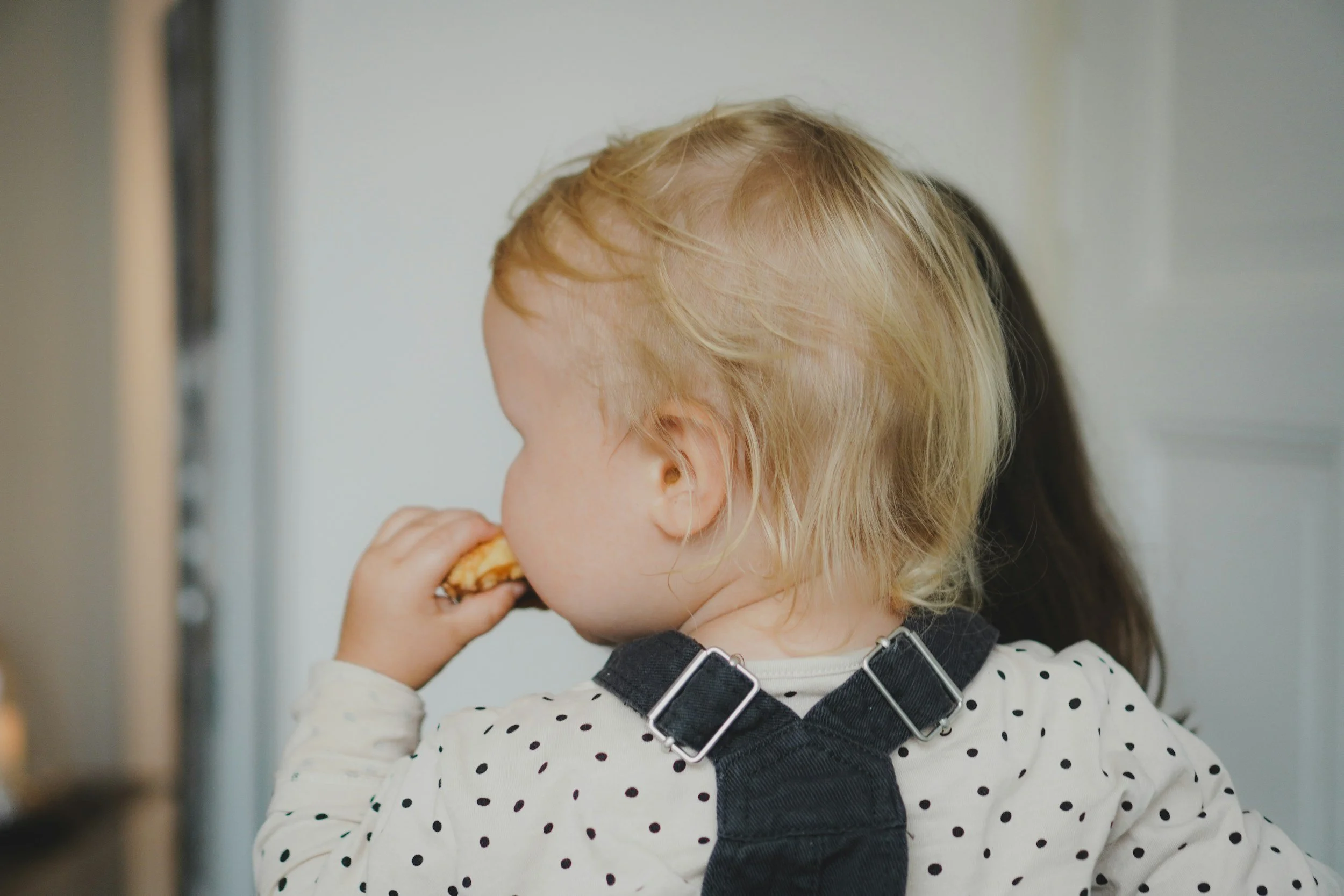 baby wth blonde hair being held by her caregiver