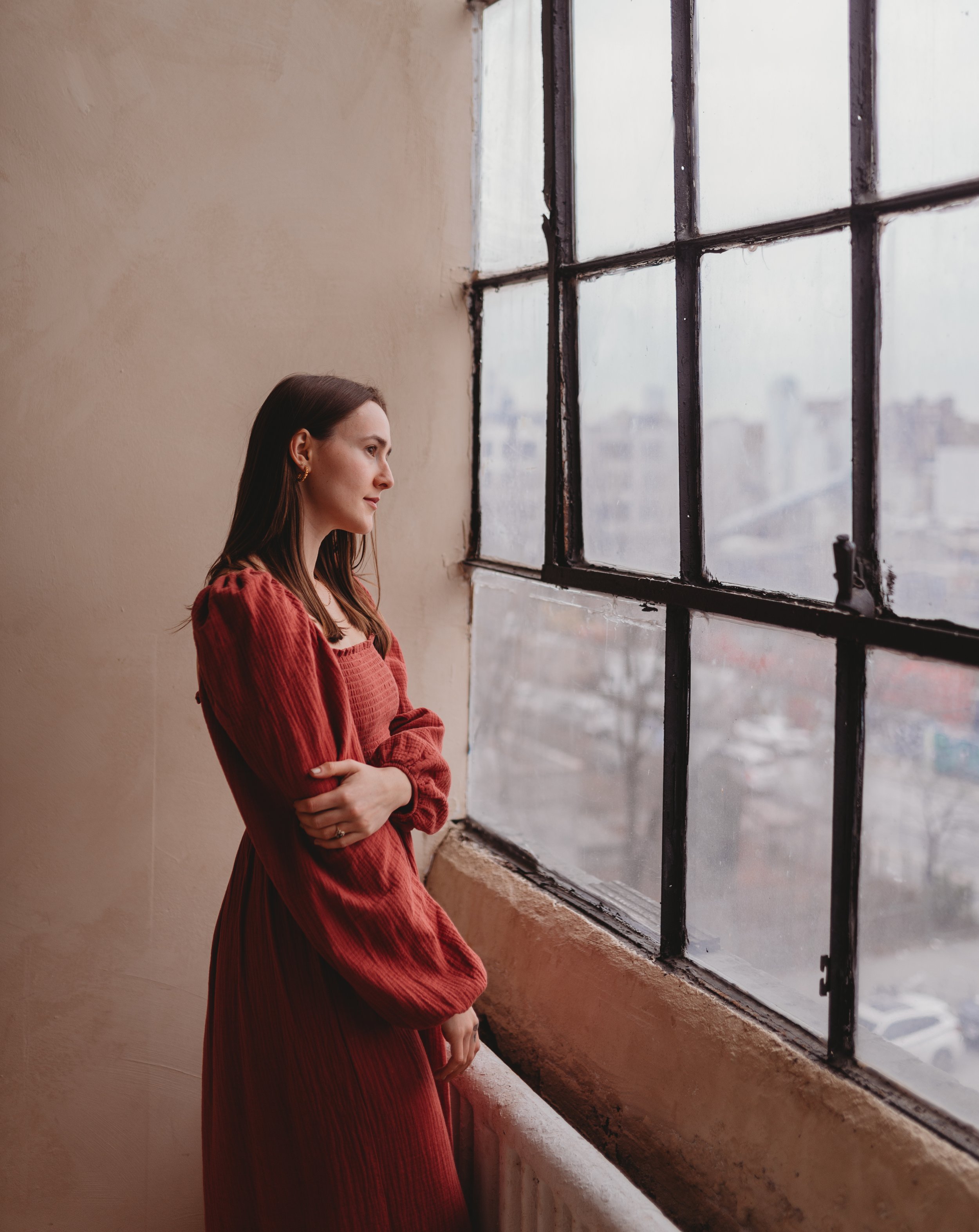 Ella Grace, sleep consultant for babies and toddlers, looking out a window in her NYC office