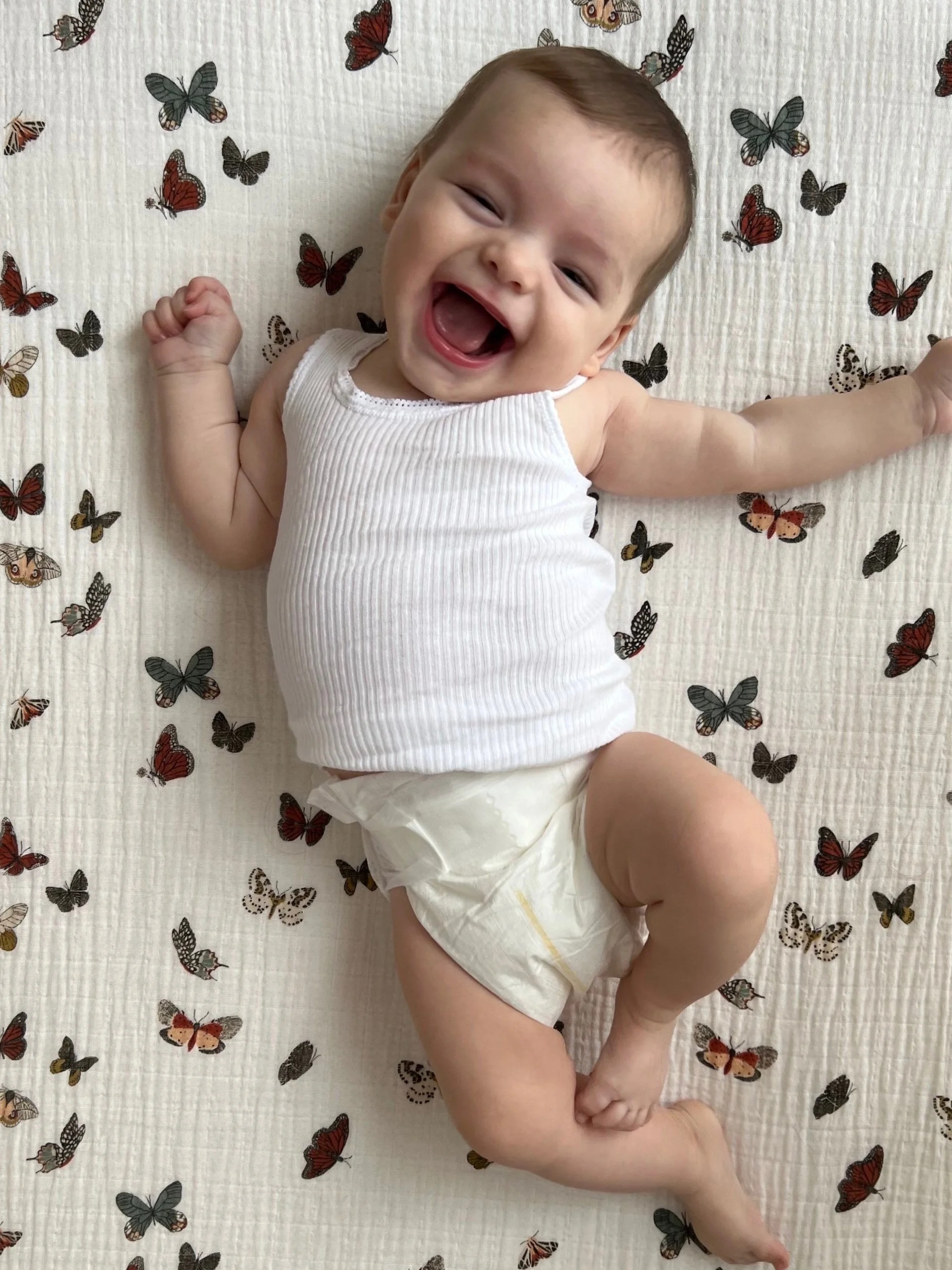 baby on butterfly sheets happy after a well-slept night