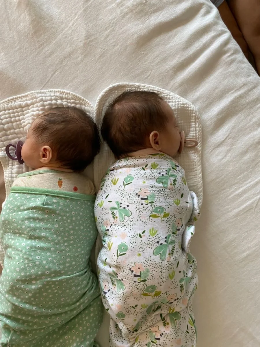 three month old twins wearing swaddles and sleeping with pacifiers
