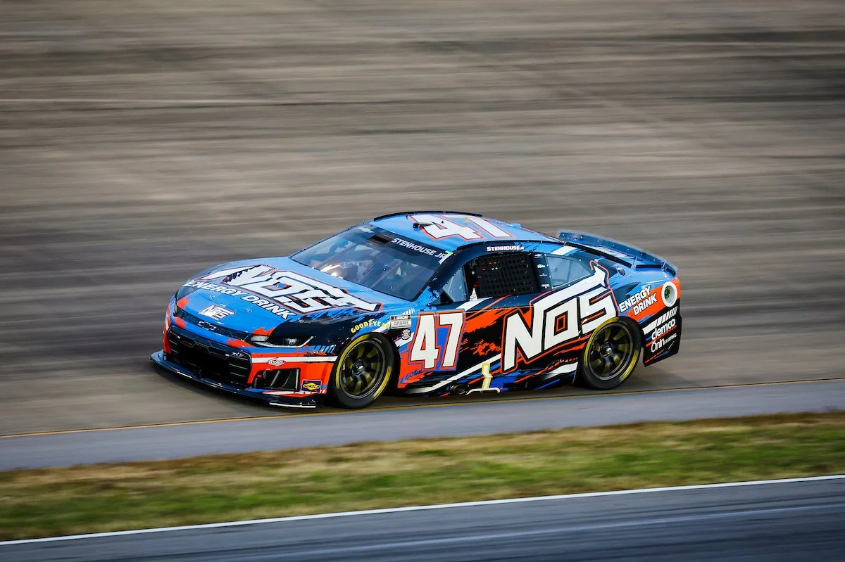 A race car on a race track with the number 47, sponsored by NOS energy drink, painted in blue, black, orange, and white.