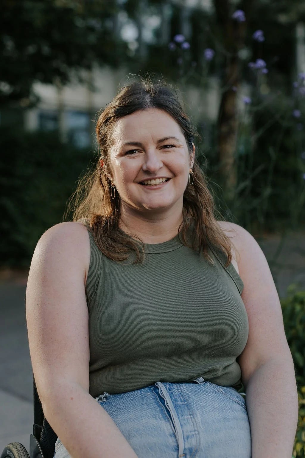 A portrait of Ali smiling at the camera with a green tank top
