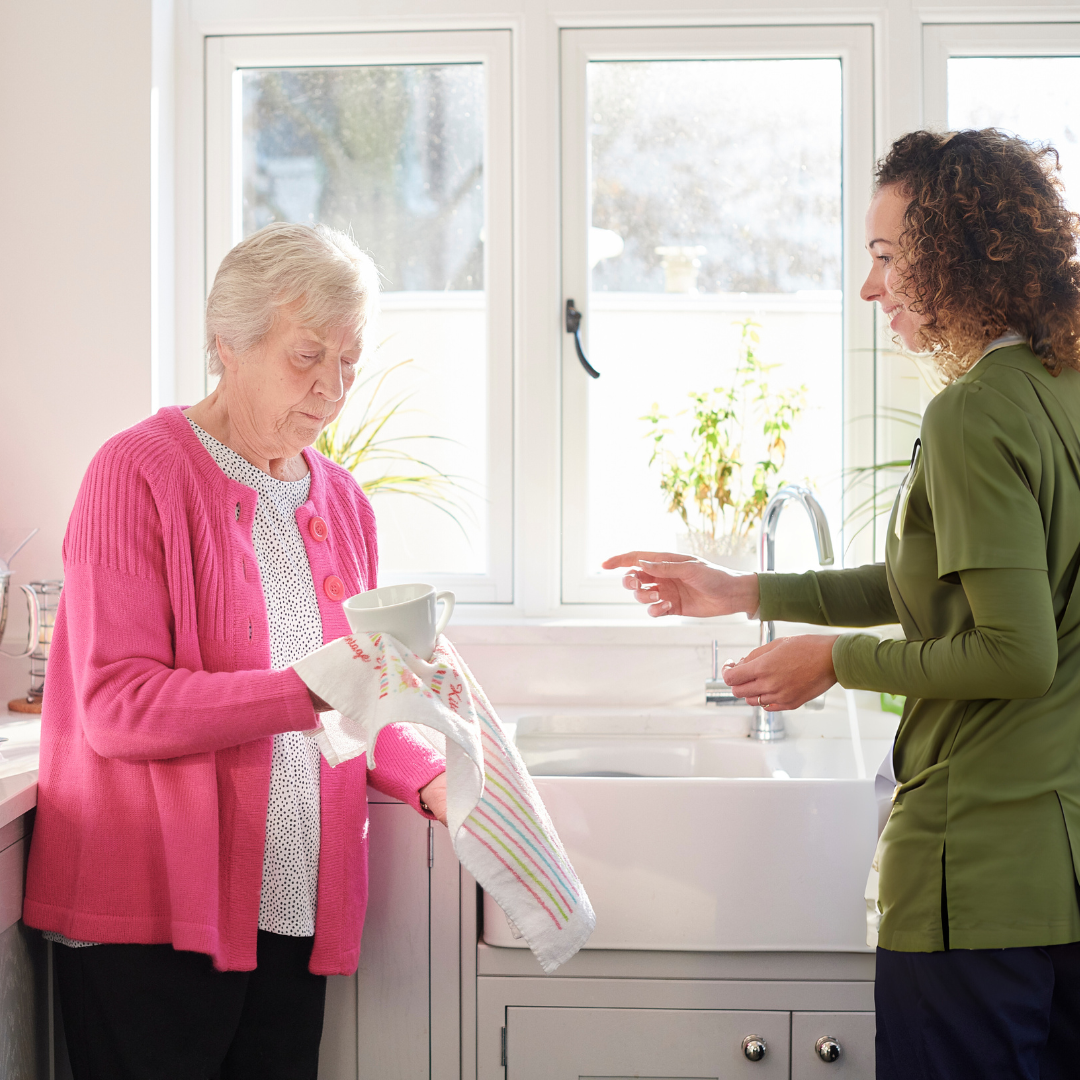 Caregiver assisting elderly client with washing her dishes