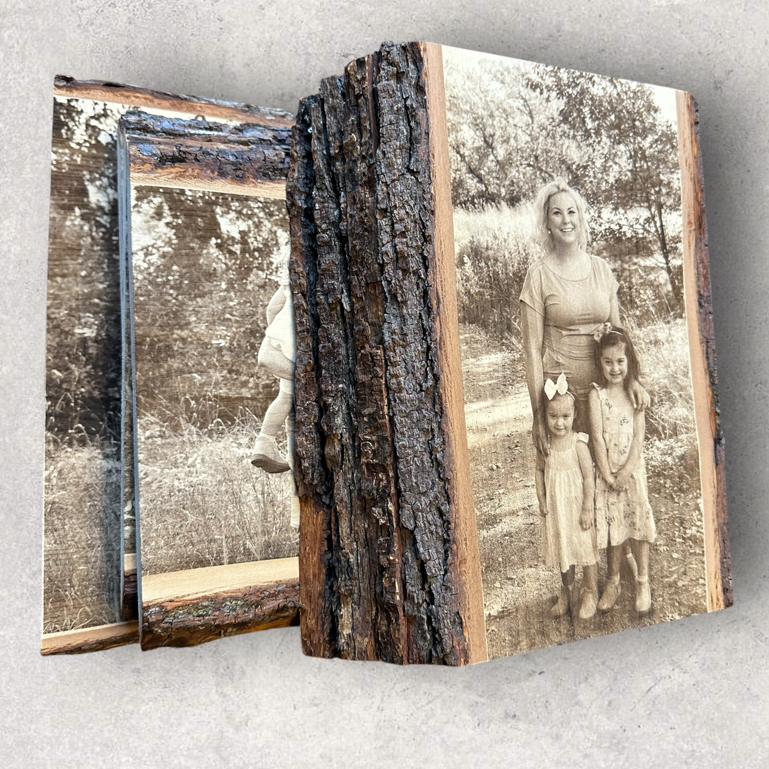Stack of custom engraved live edge wood photo plaques, featuring a mother with two young daughters outdoors