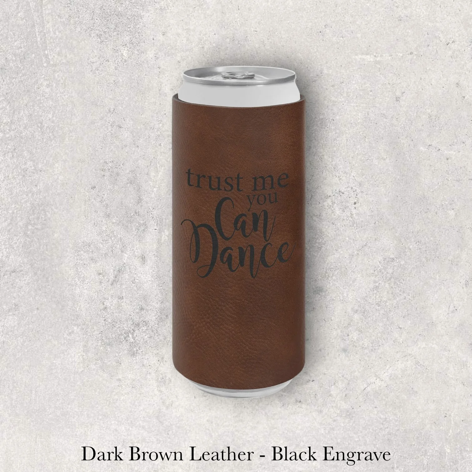 Dark brown leather slim can coozie with black laser-engraved “Trust Me You Can Dance” text design, engraved by Lazeric