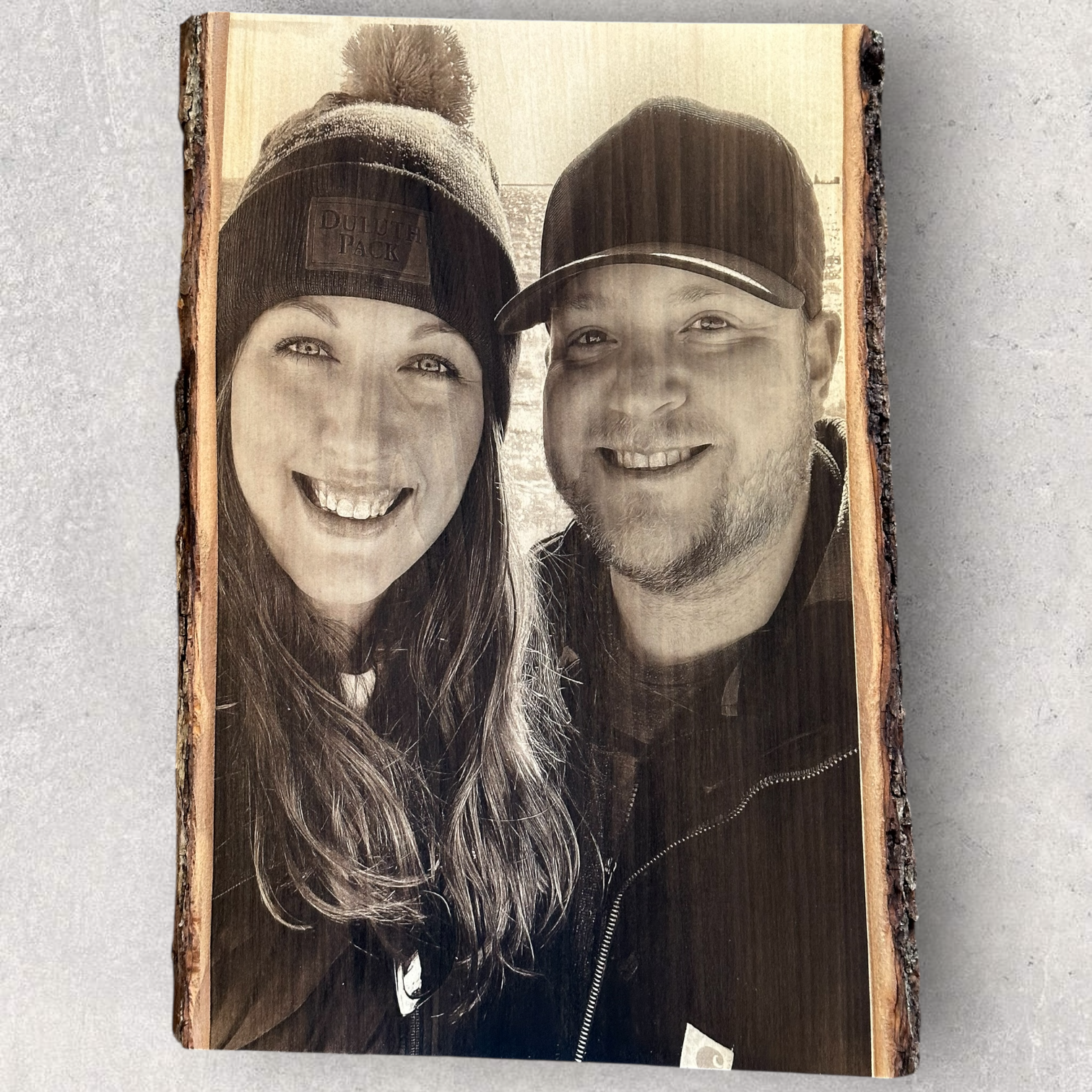 Custom photo engraving of a smiling couple on live edge wood slab with bark edge
