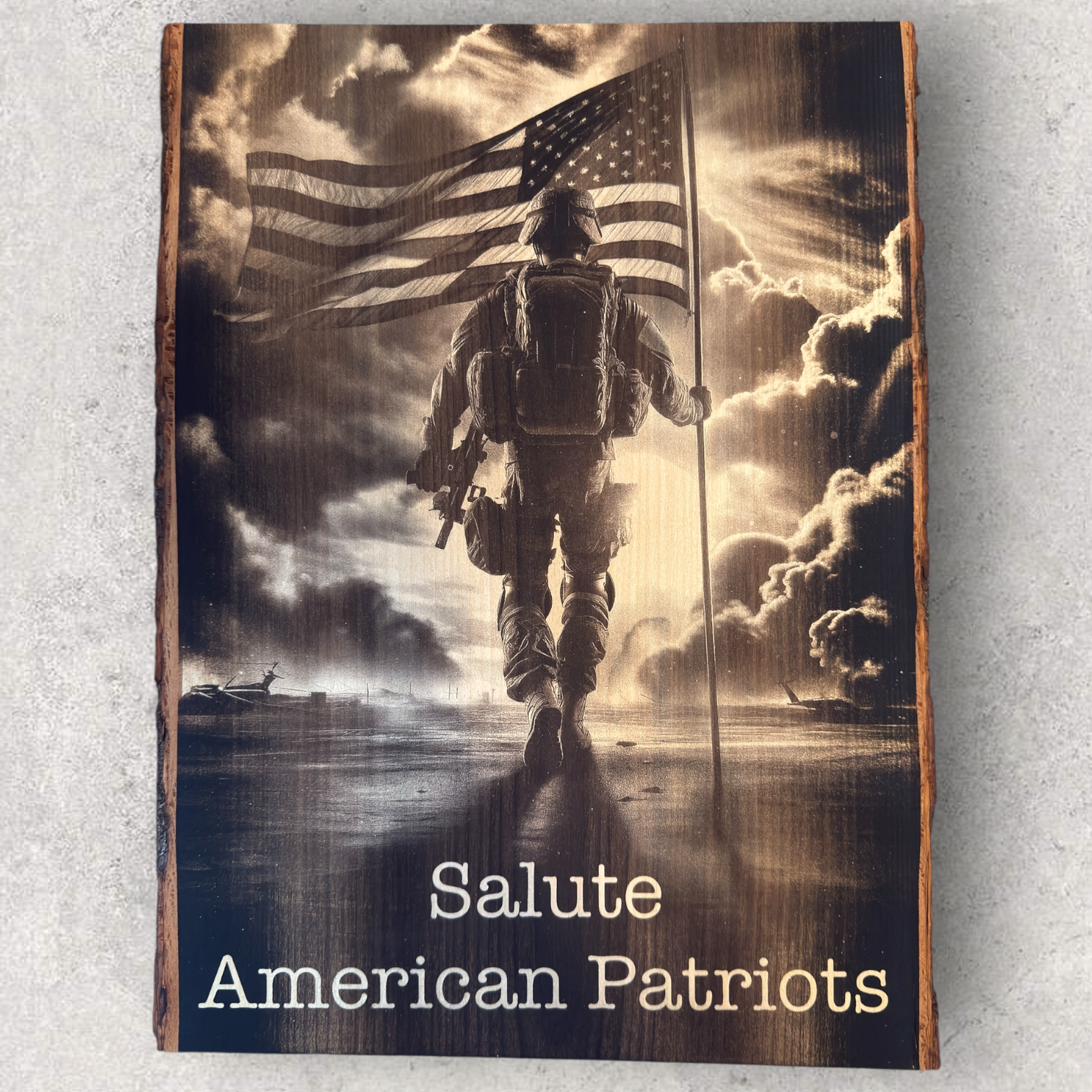 Military tribute engraving of soldier holding American flag with 'Salute American Patriots' text on bark-edged wood