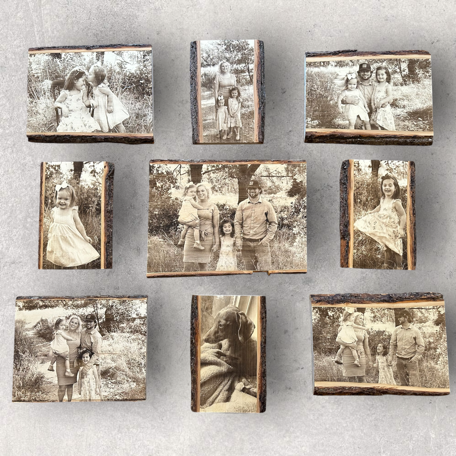 Collection of laser engraved family and pet photos on live edge basswood blocks, featuring natural bark edges and rustic wood grain, arranged on a light concrete background.