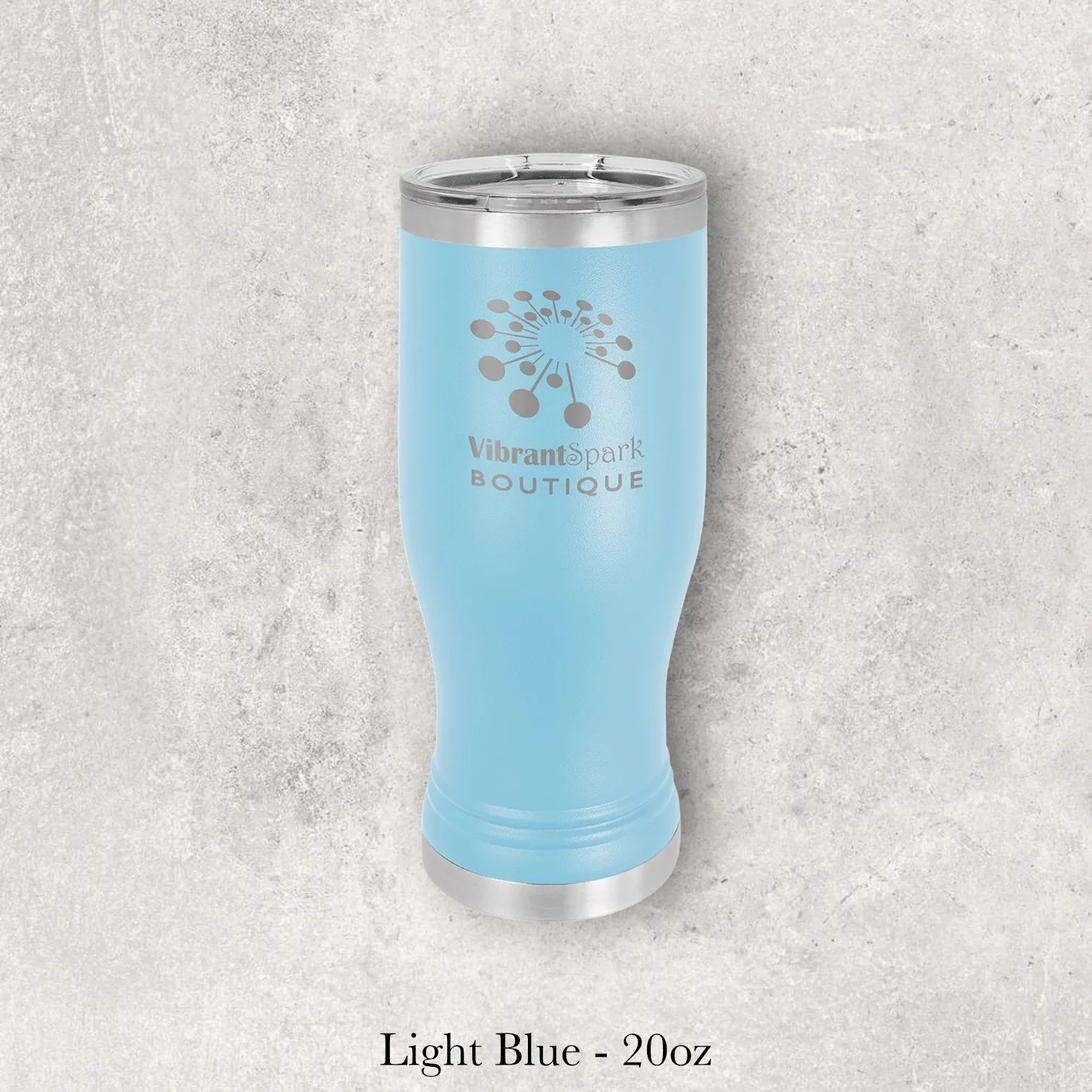 Light blue 20oz pilsner-style tumbler engraved by Lazeric with the Vibrant Spark Boutique logo.