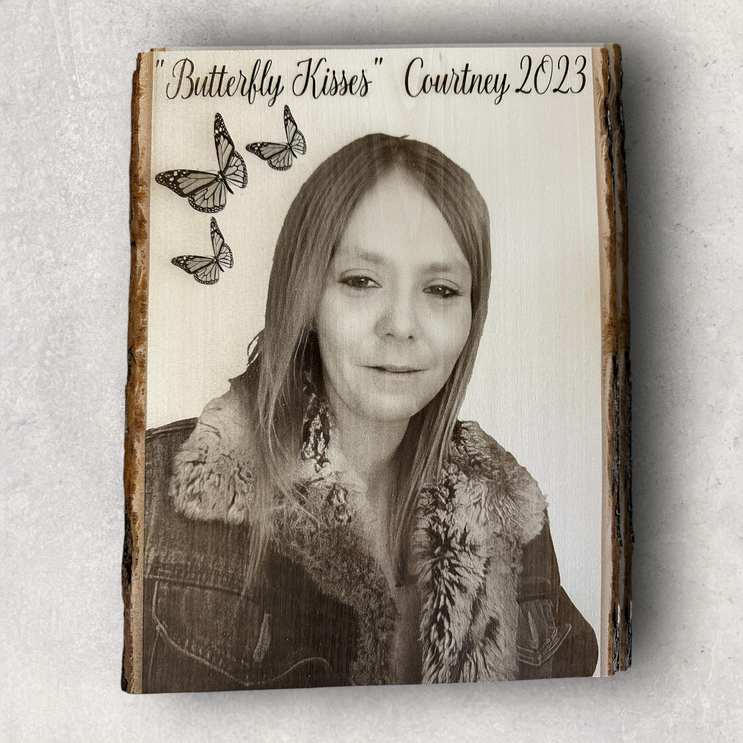 Custom memorial portrait of a young woman with butterfly accents and personalized text, engraved on live edge wood