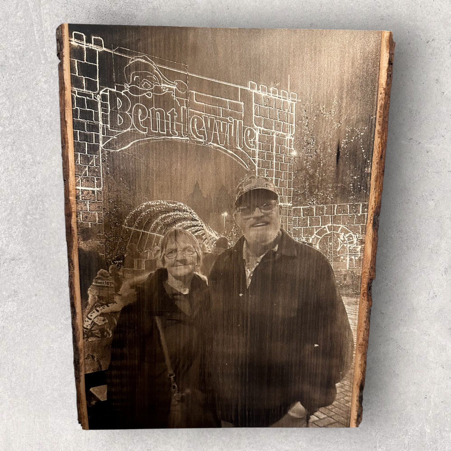 Laser engraved photo of an older couple visiting Bentleyville holiday lights, engraved on rustic live edge wood