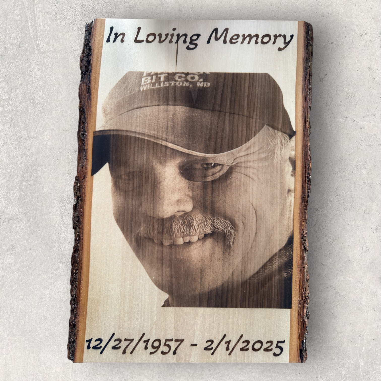 In loving memory wood engraving of a man wearing a cap with name and date, on live edge hardwood