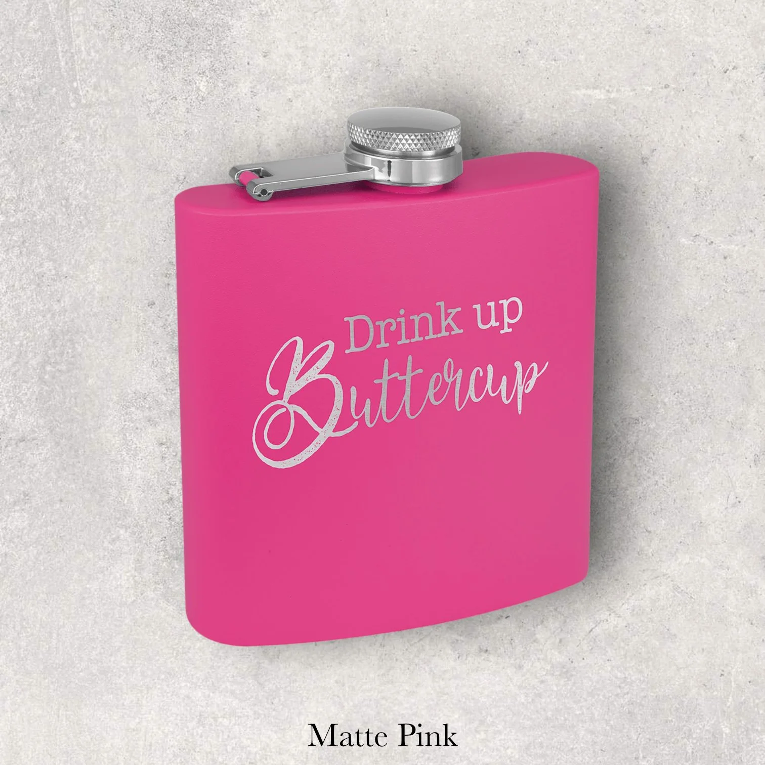 Matte pink 6oz metal flask engraved with “Drink up Buttercup” script text, engraved by Lazeric