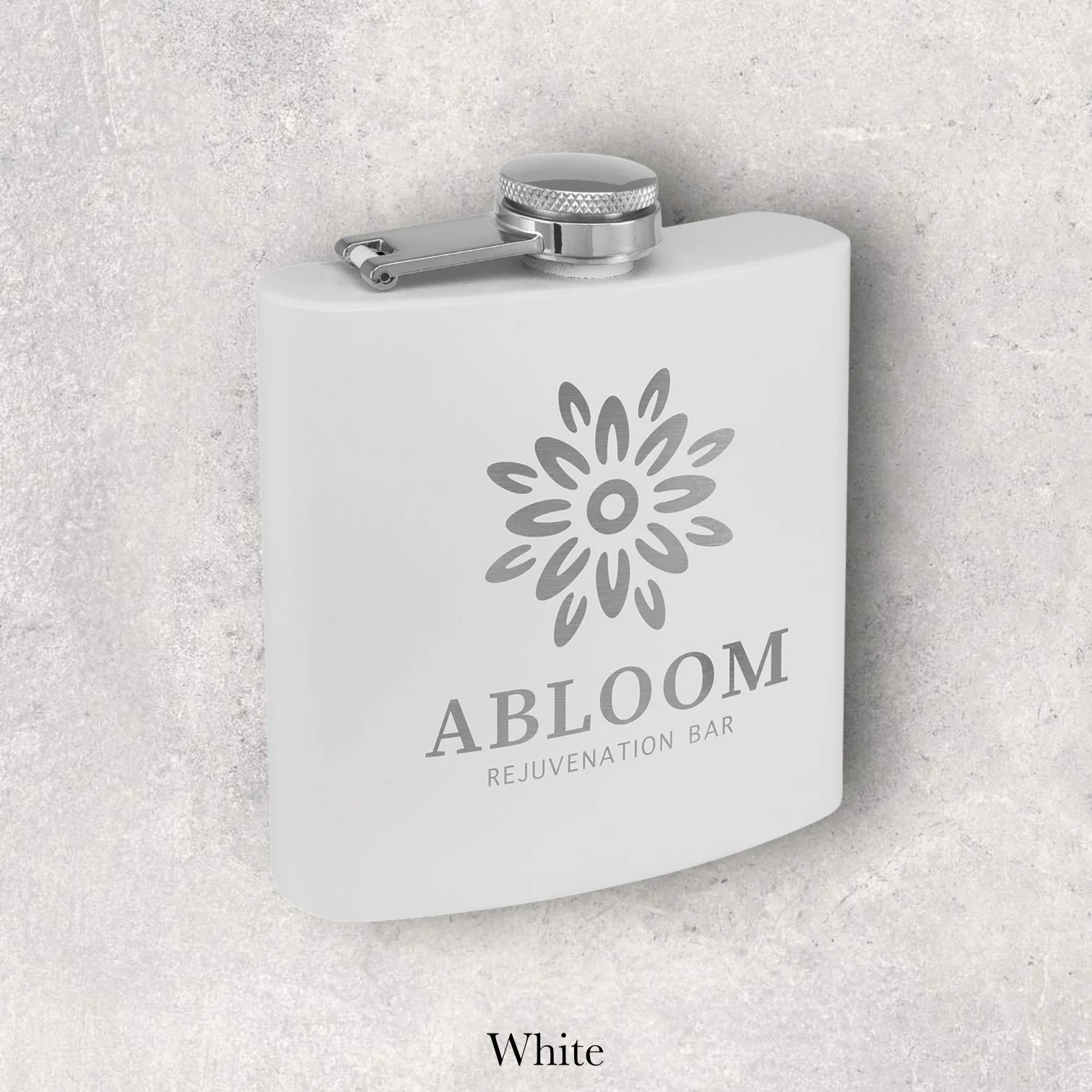 White 6oz metal flask engraved with A Bloom Rejuvenation Bar floral logo, engraved by Lazeric