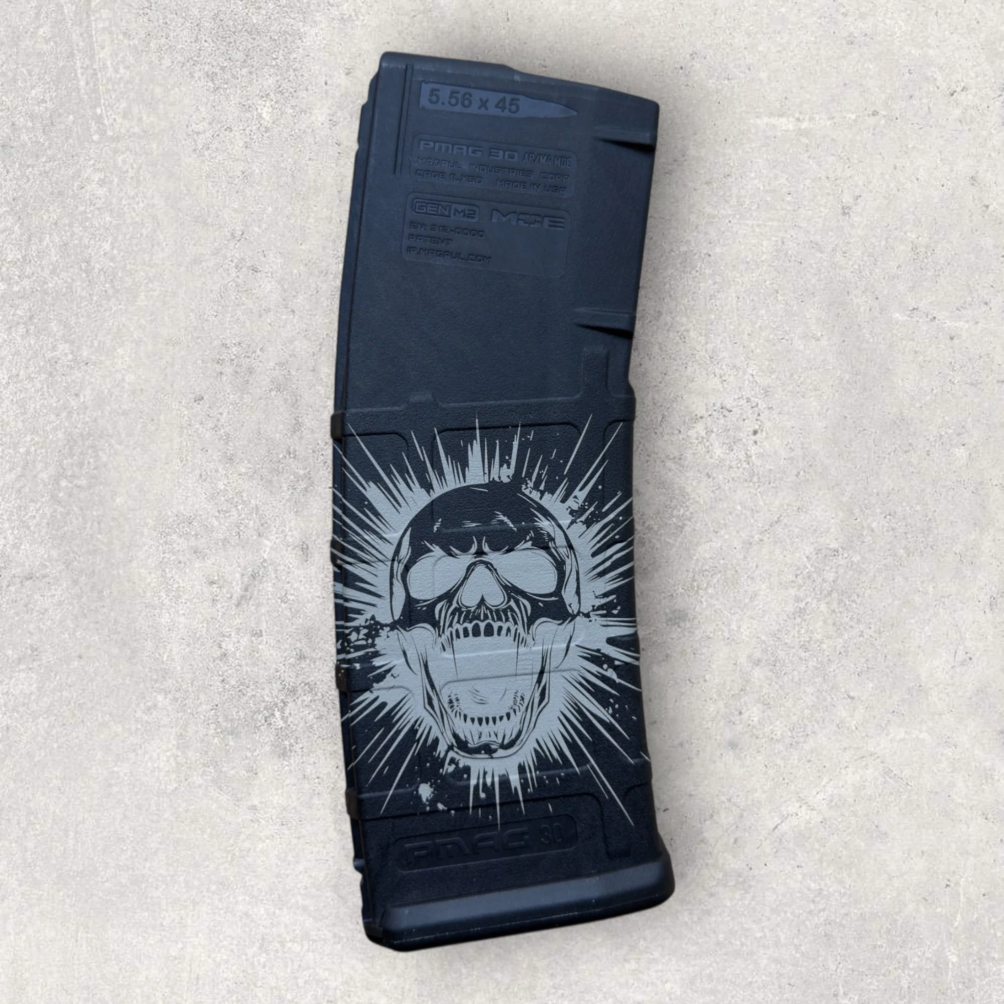 Custom laser-engraved AR-15 magazine with a detailed skull graphic etched into the surface, showcasing precision firearm accessory engraving by Lazeric.