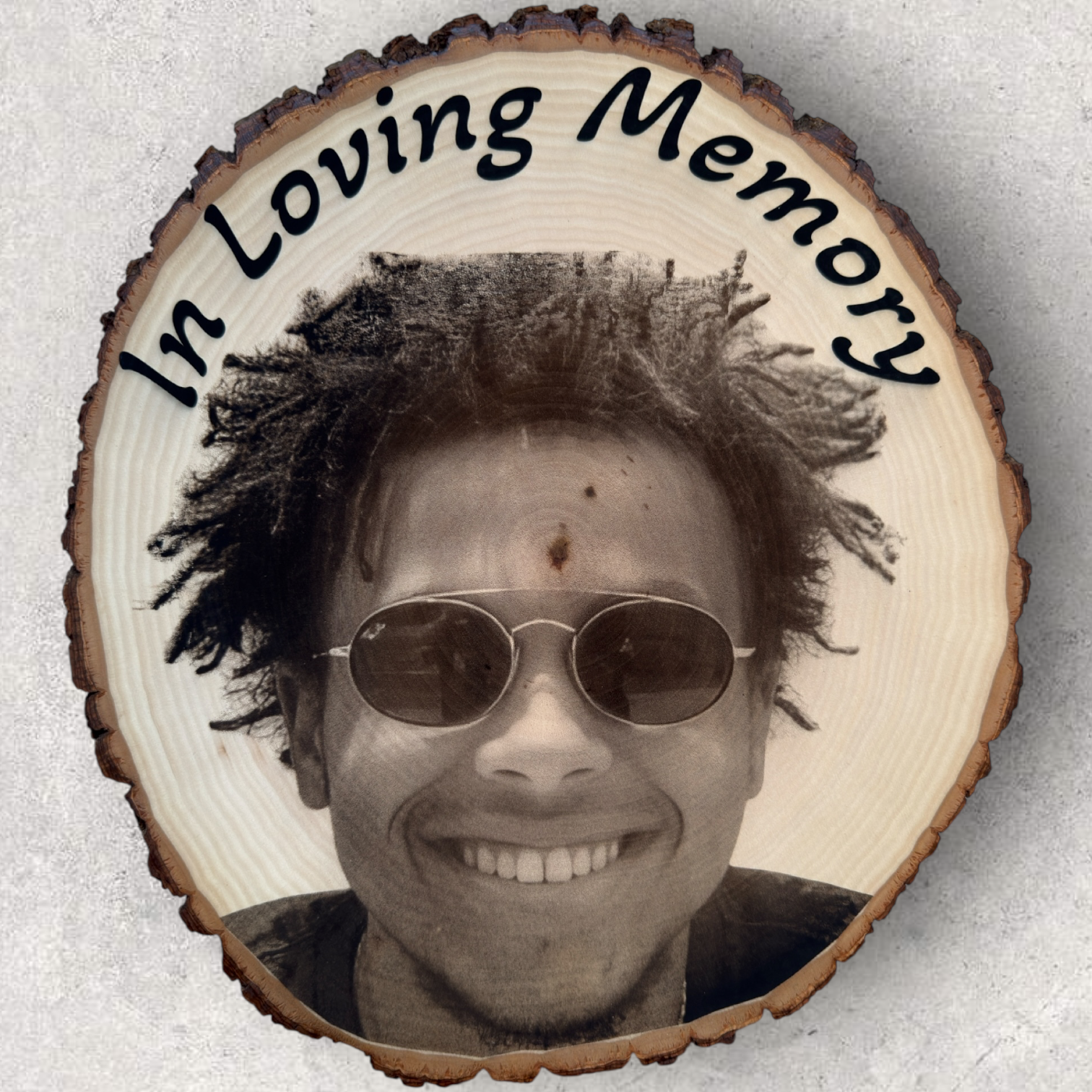Laser engraved memorial portrait on round live edge basswood slab with ‘In Loving Memory’ text and bark border, featuring a smiling man in sunglasses - Lazeric