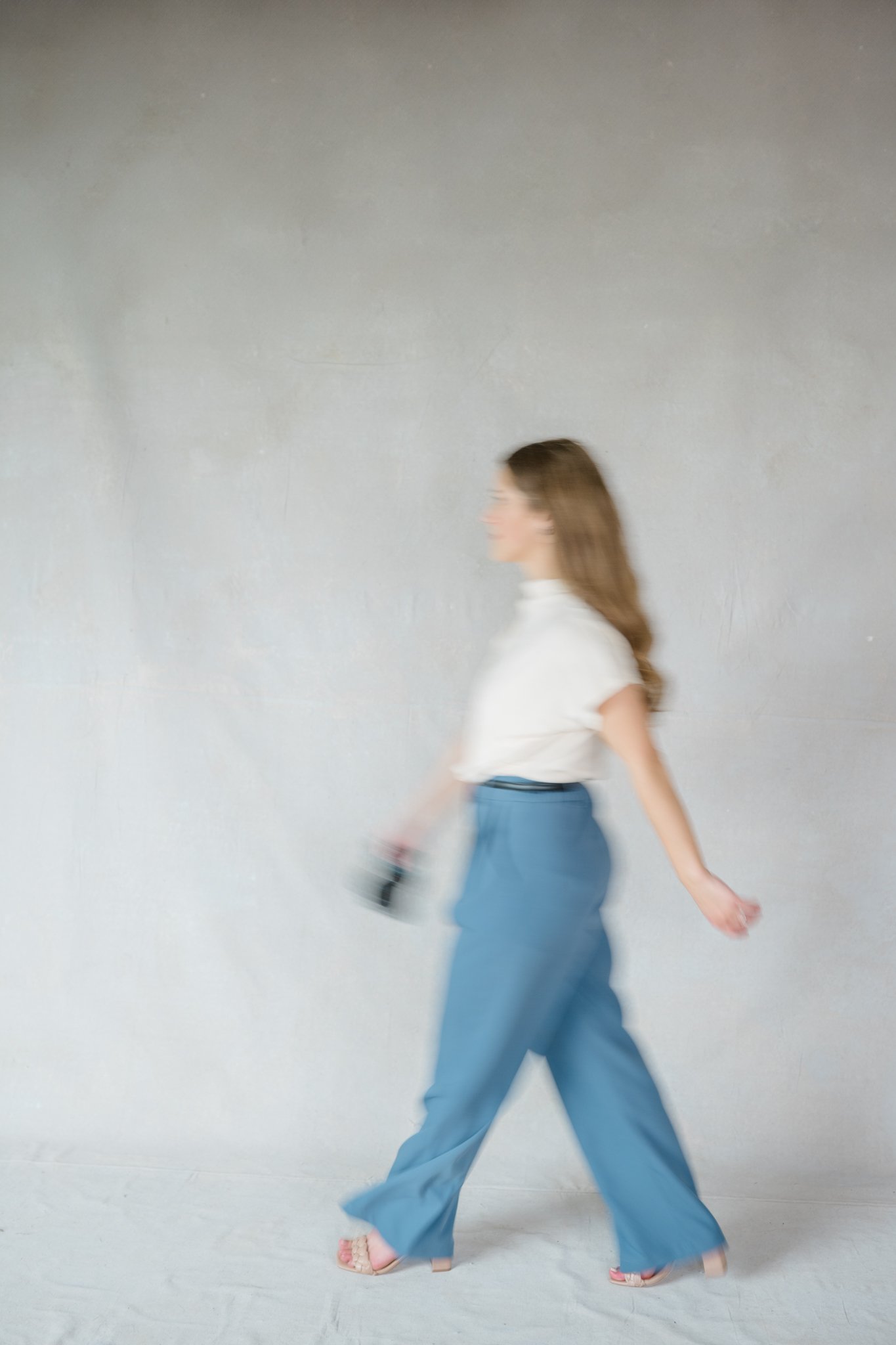 Motion blur photo of woman walking across the frame for branding photography session.