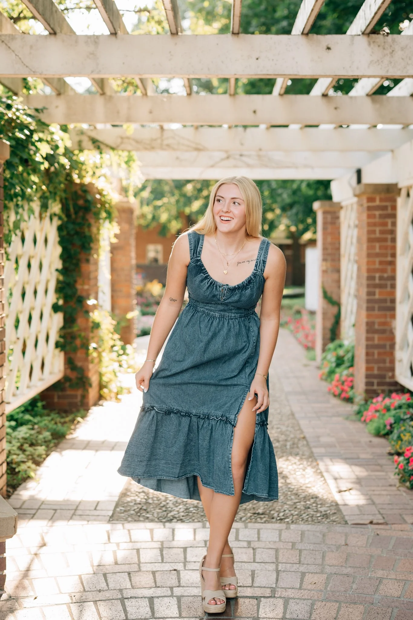 Girl laughs, looking somewhere off camera while wandering through gardens for her Omaha senior pictures.