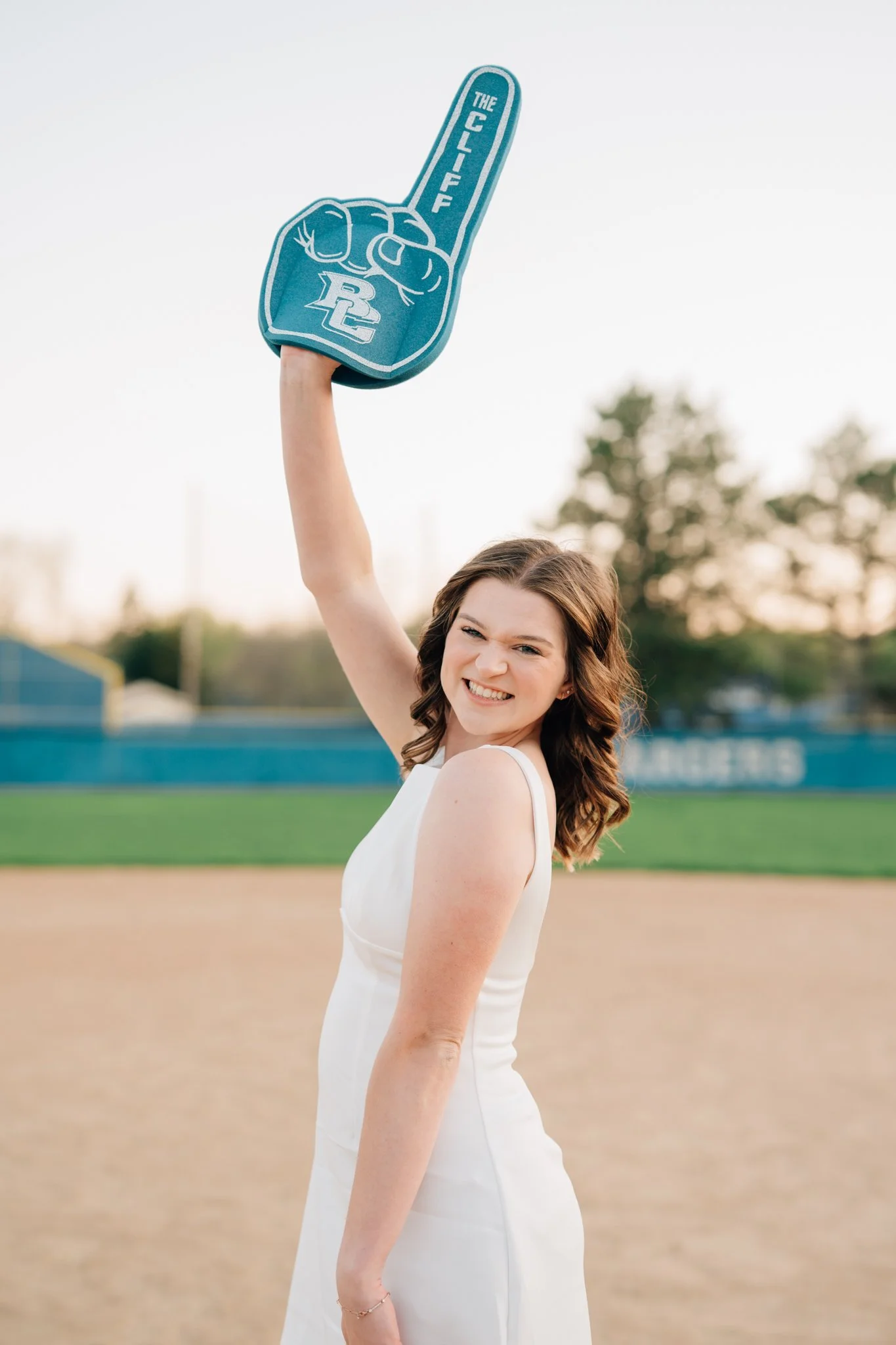 Girl poses with giant foam finger to celebrate college graduation during photography session.